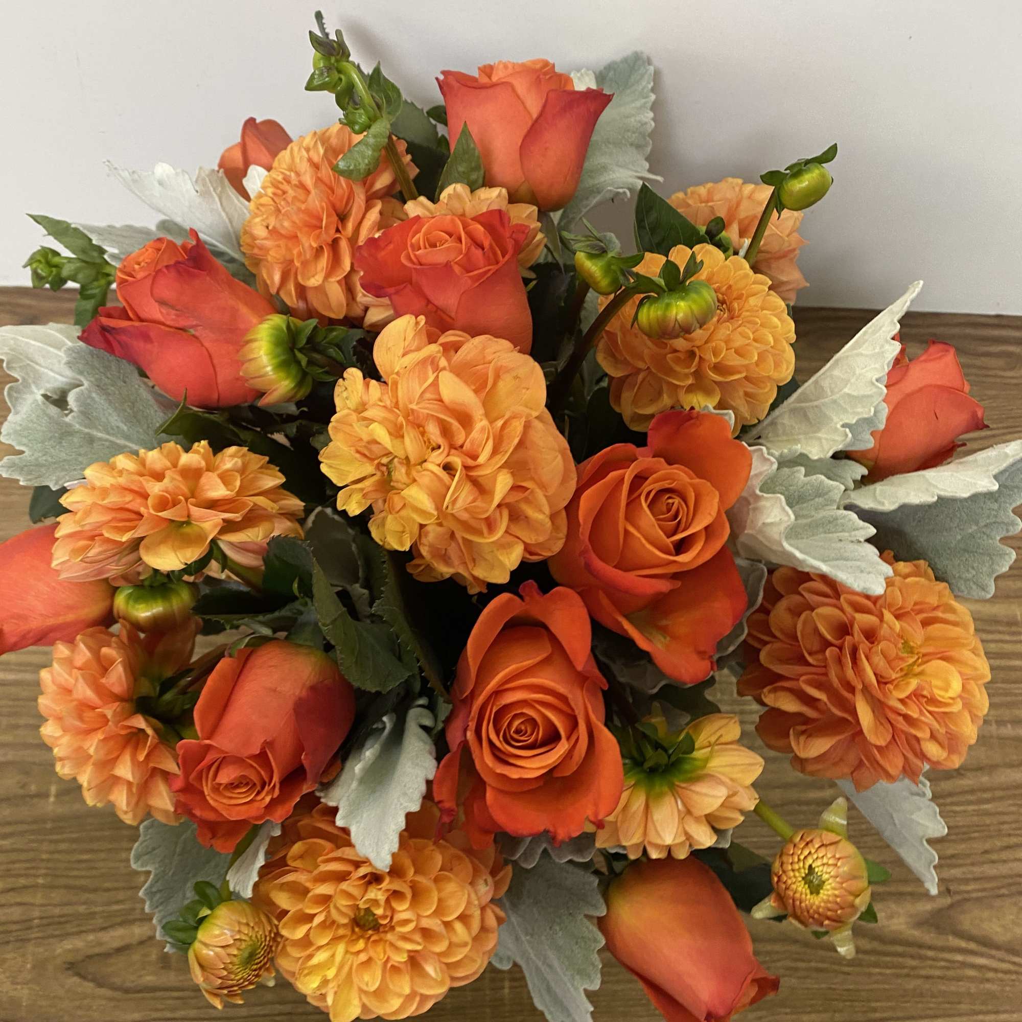 In a glass vase combinations of orange dollar and orange roses