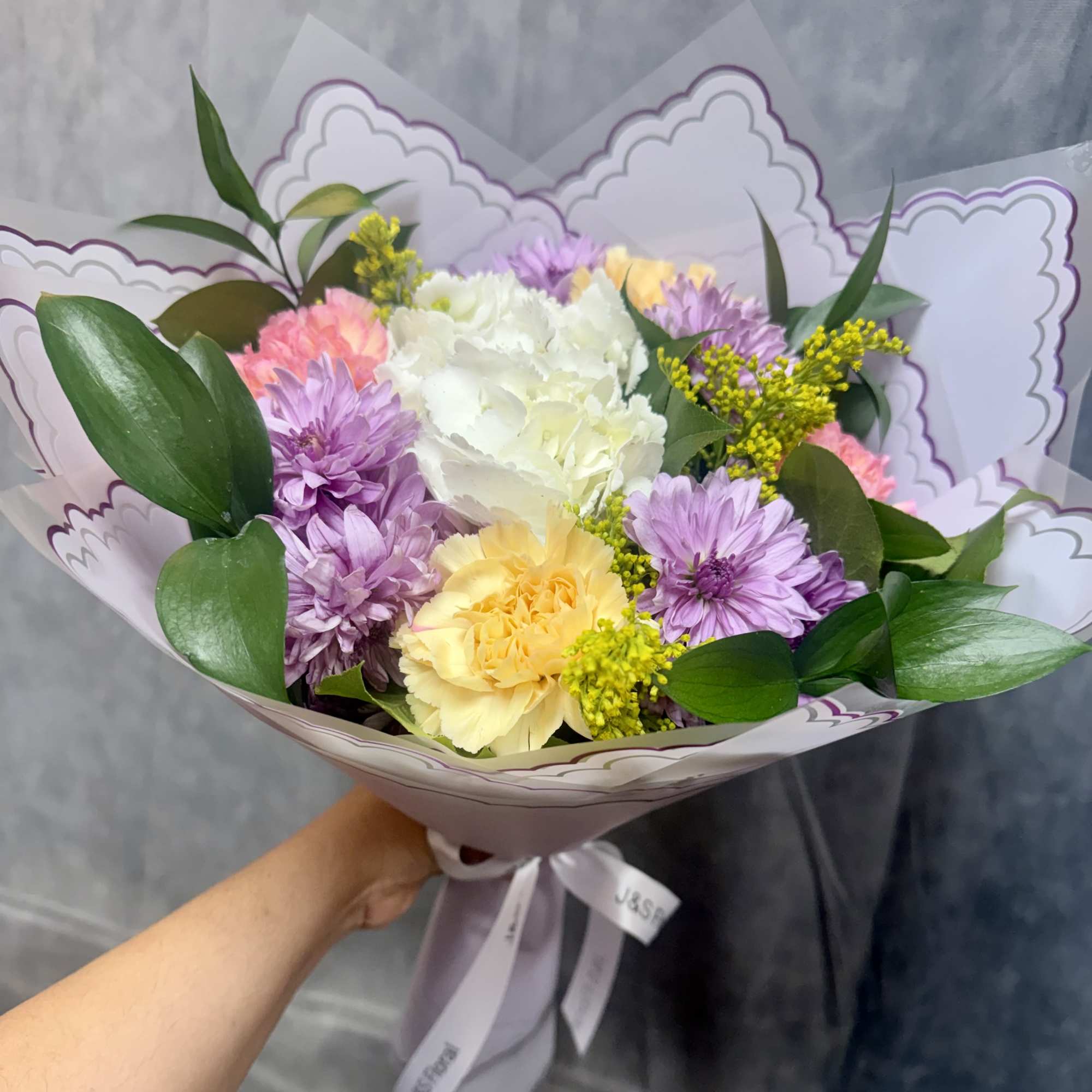 A soft and elegant mix of lavender mums, creamy hydrangea, buttery yellow