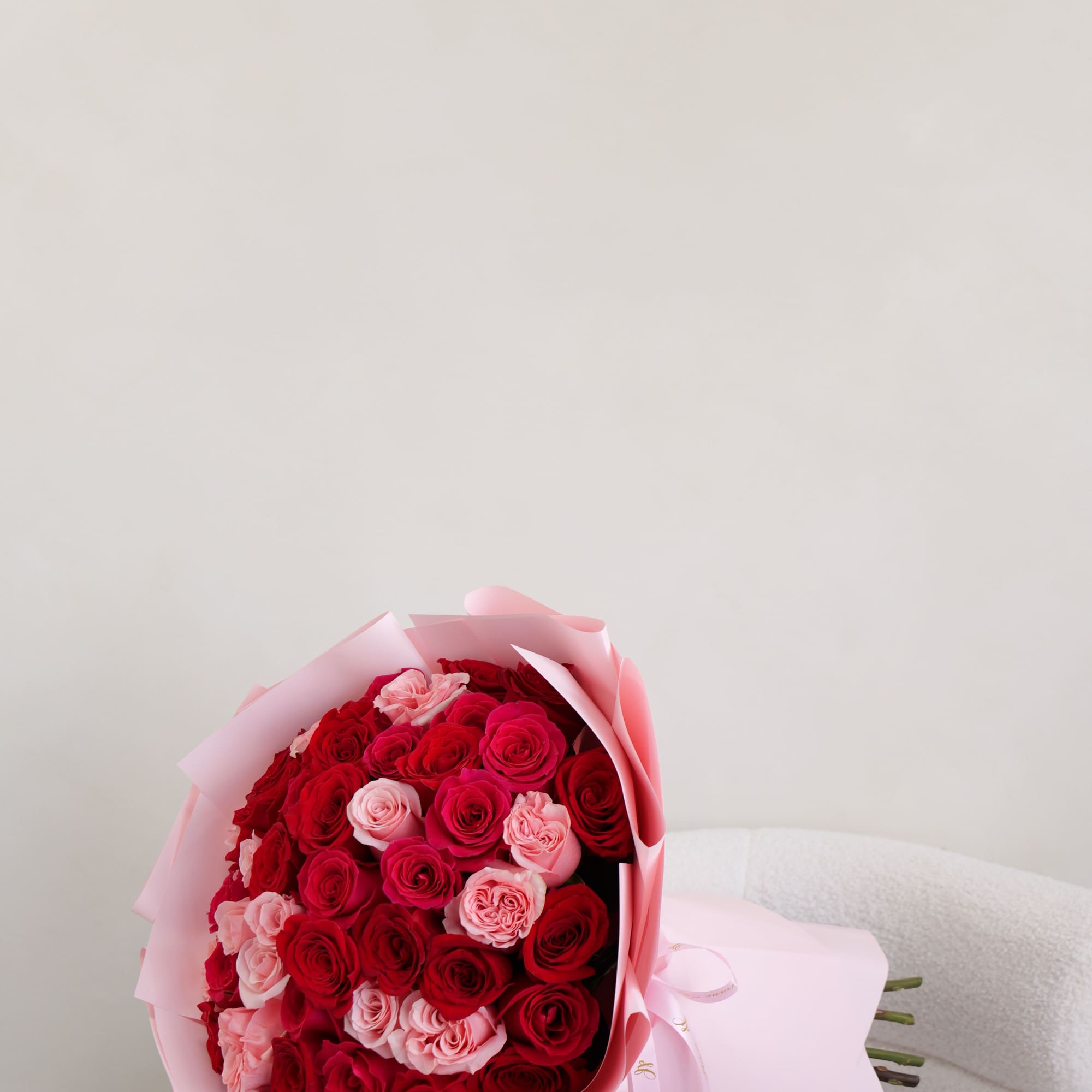 A beautifully arranged bouquet of fresh red and soft pink roses, wrapped
