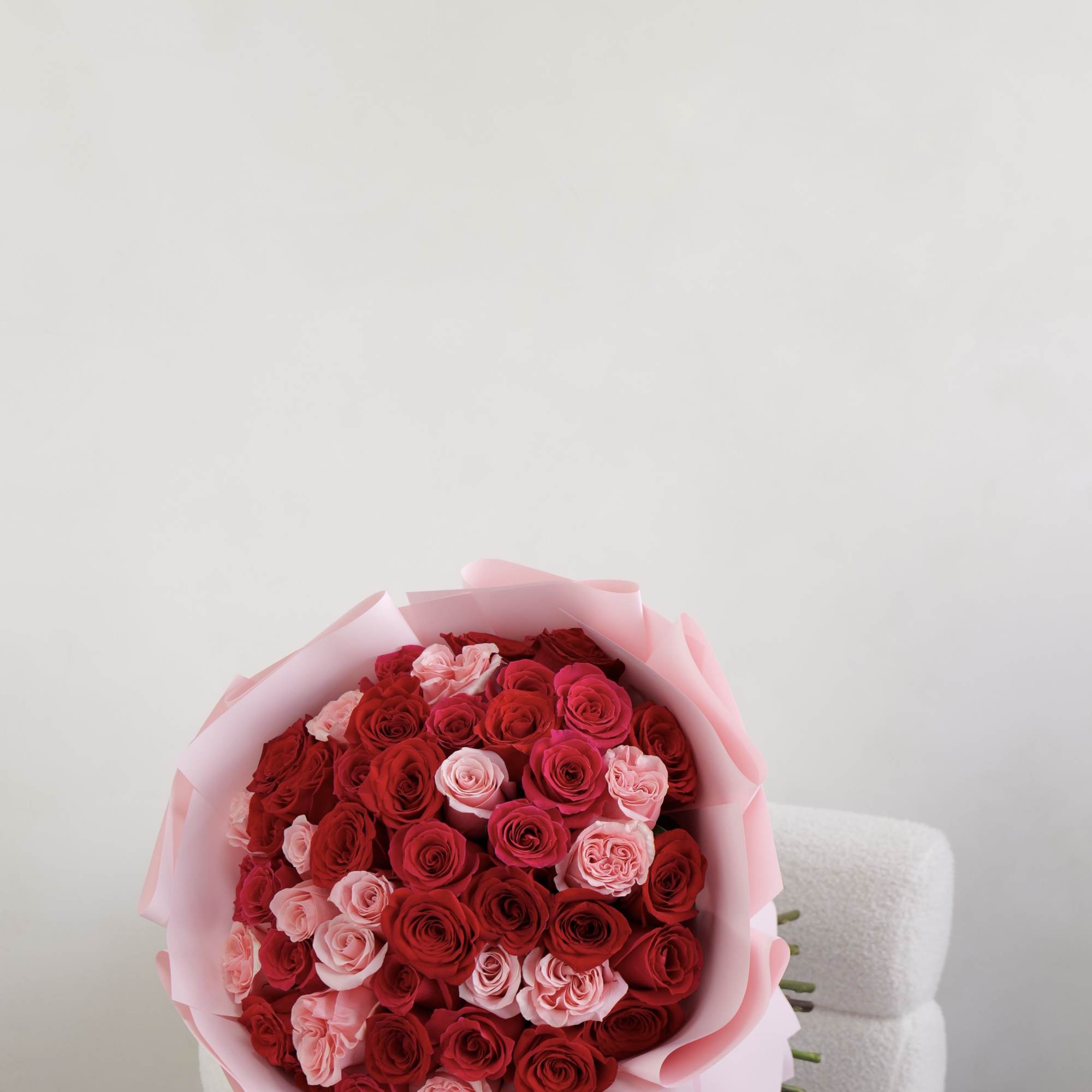 A beautifully arranged bouquet of fresh red and soft pink roses, wrapped