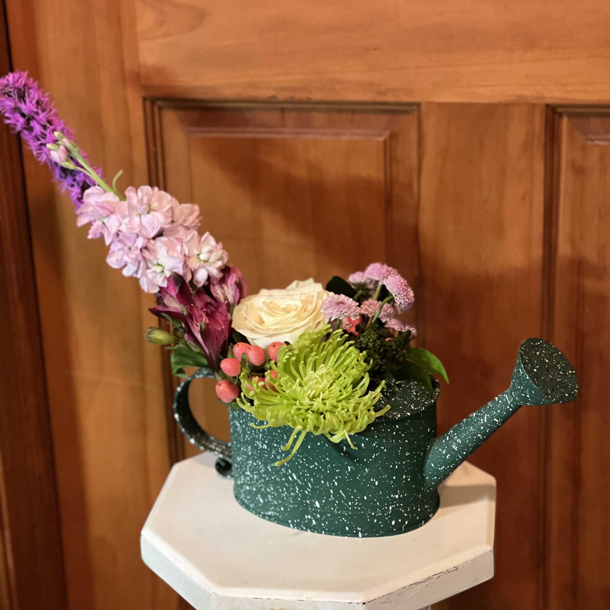 Mixed flowers arranged in a green watering can
