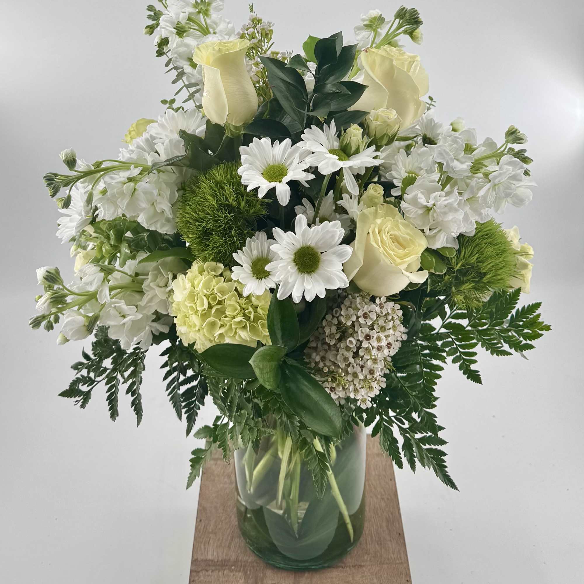 This exquisite arrangement features a delicate combination of white roses, green ball