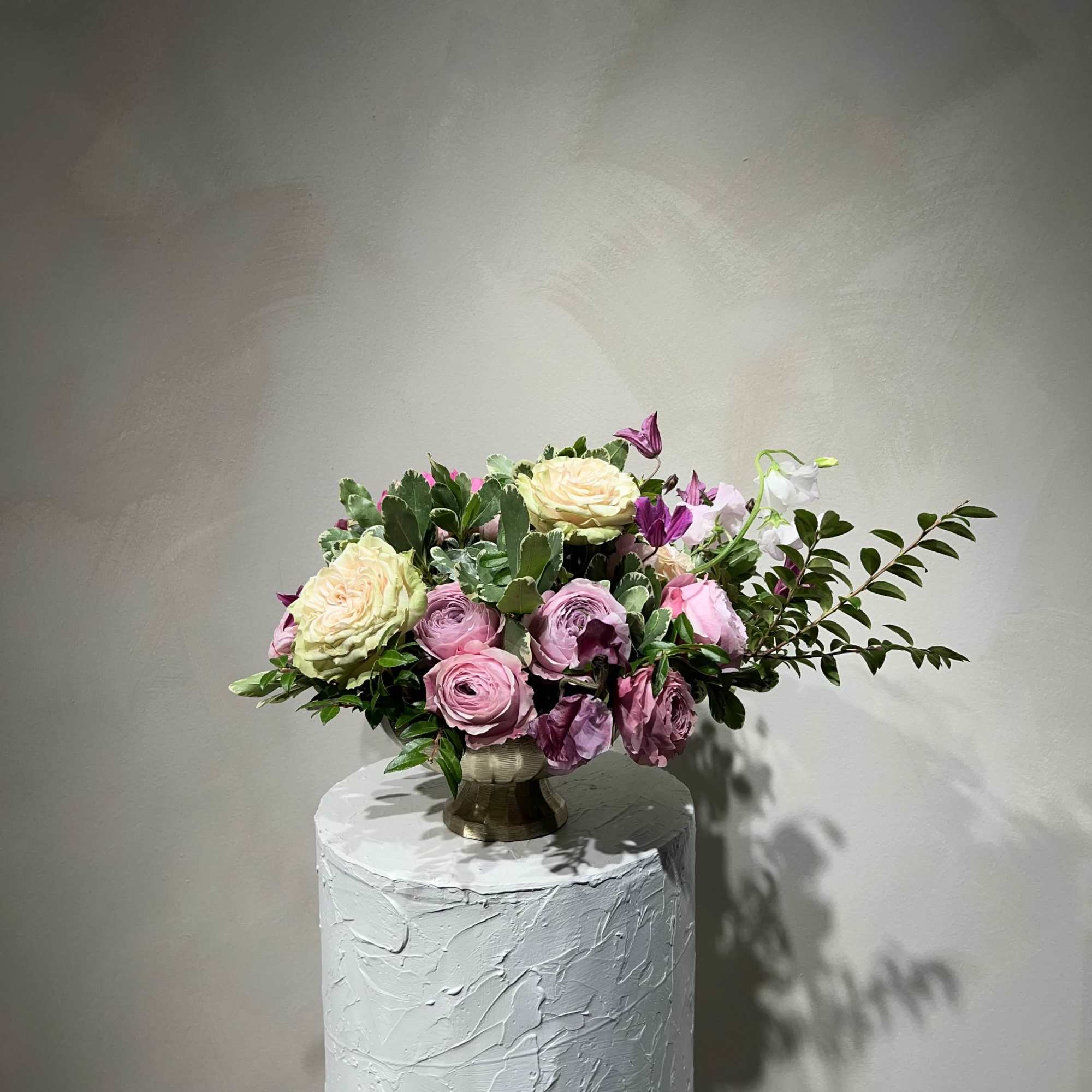 Pink and cream roses arranged in a gold vase