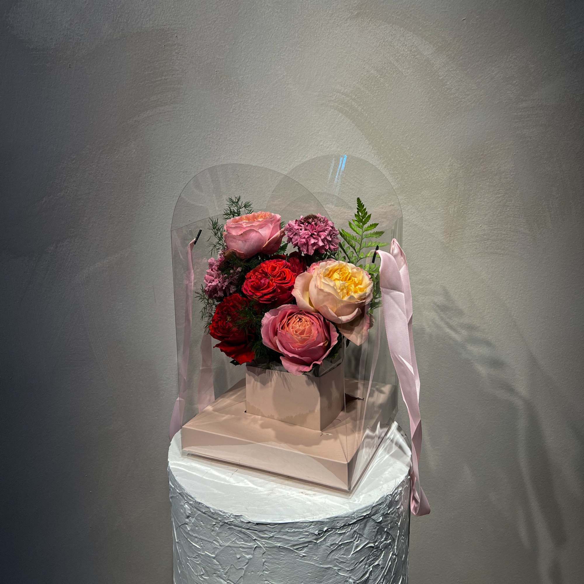 Pink and red rose bouquet in a clear gift box with ribbon