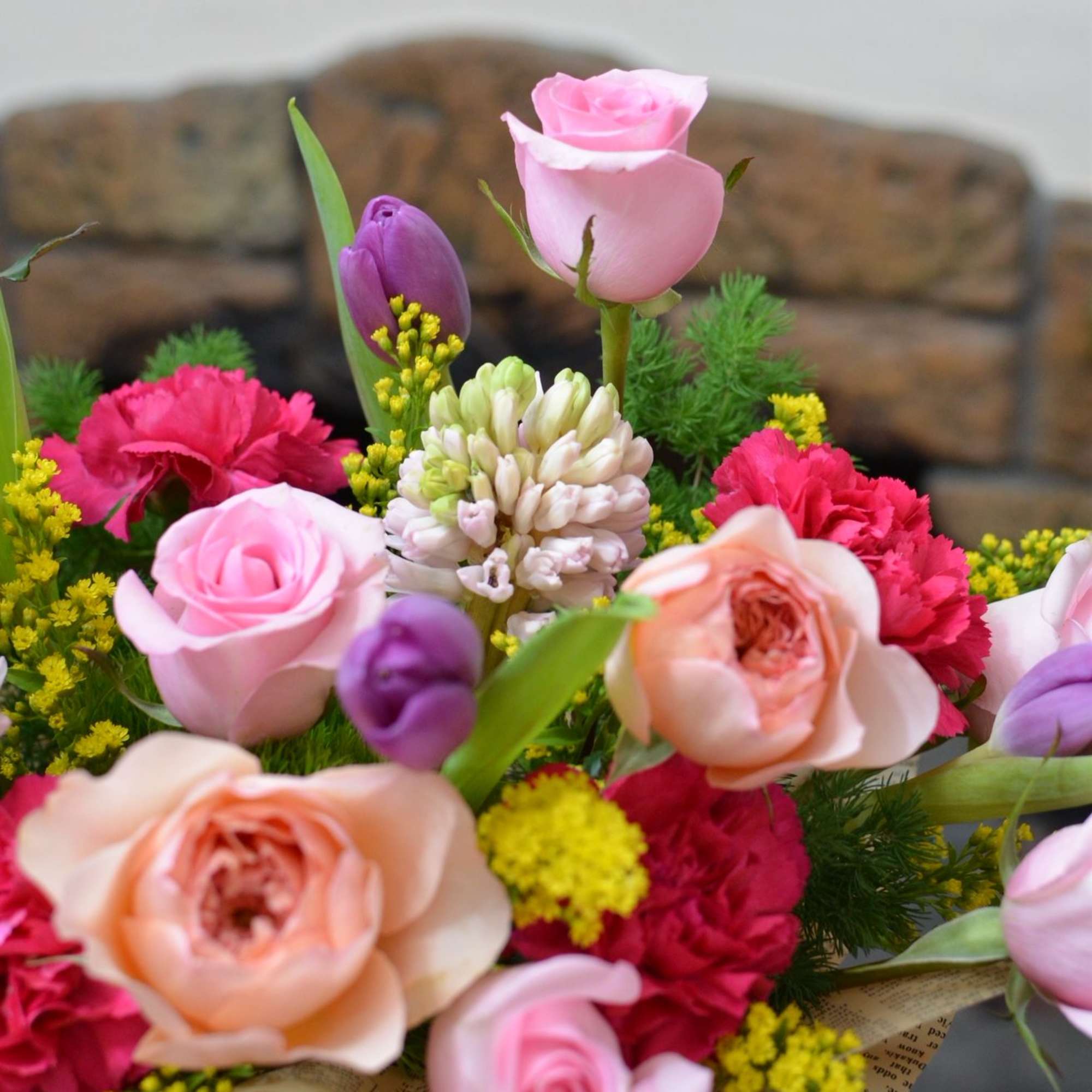 A couture-inspired floral handbag arrangement featuring sculpted tulips, premium roses, and fragrant