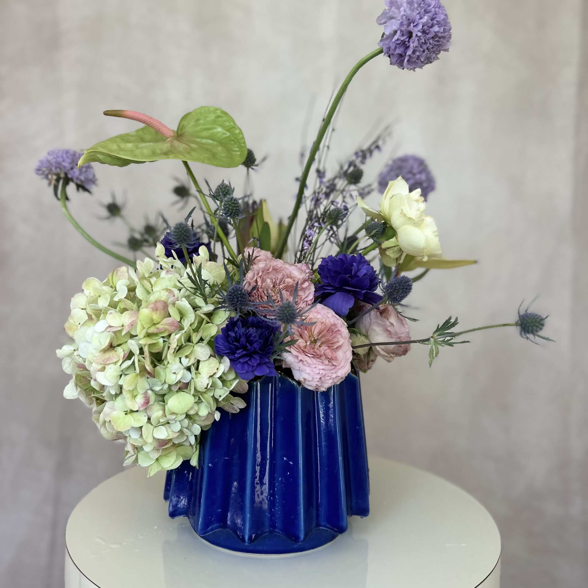 Set in a stunning blue vessel, this lavender, pink and white composition