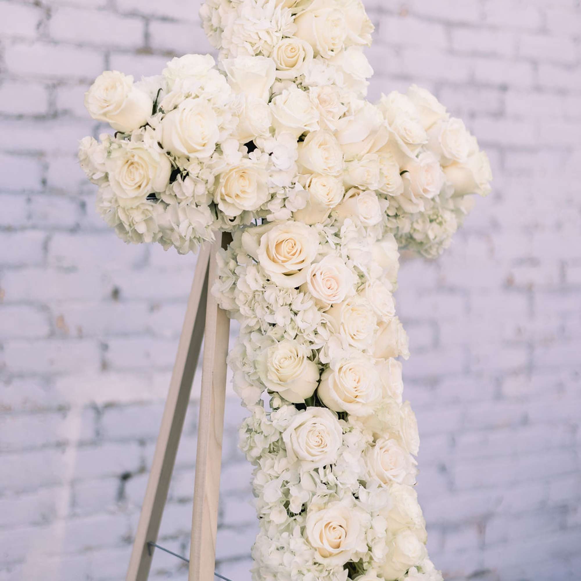 Easel stand cross-shaped spray designed with roses &amp; hydrangea. 
Mounted on a