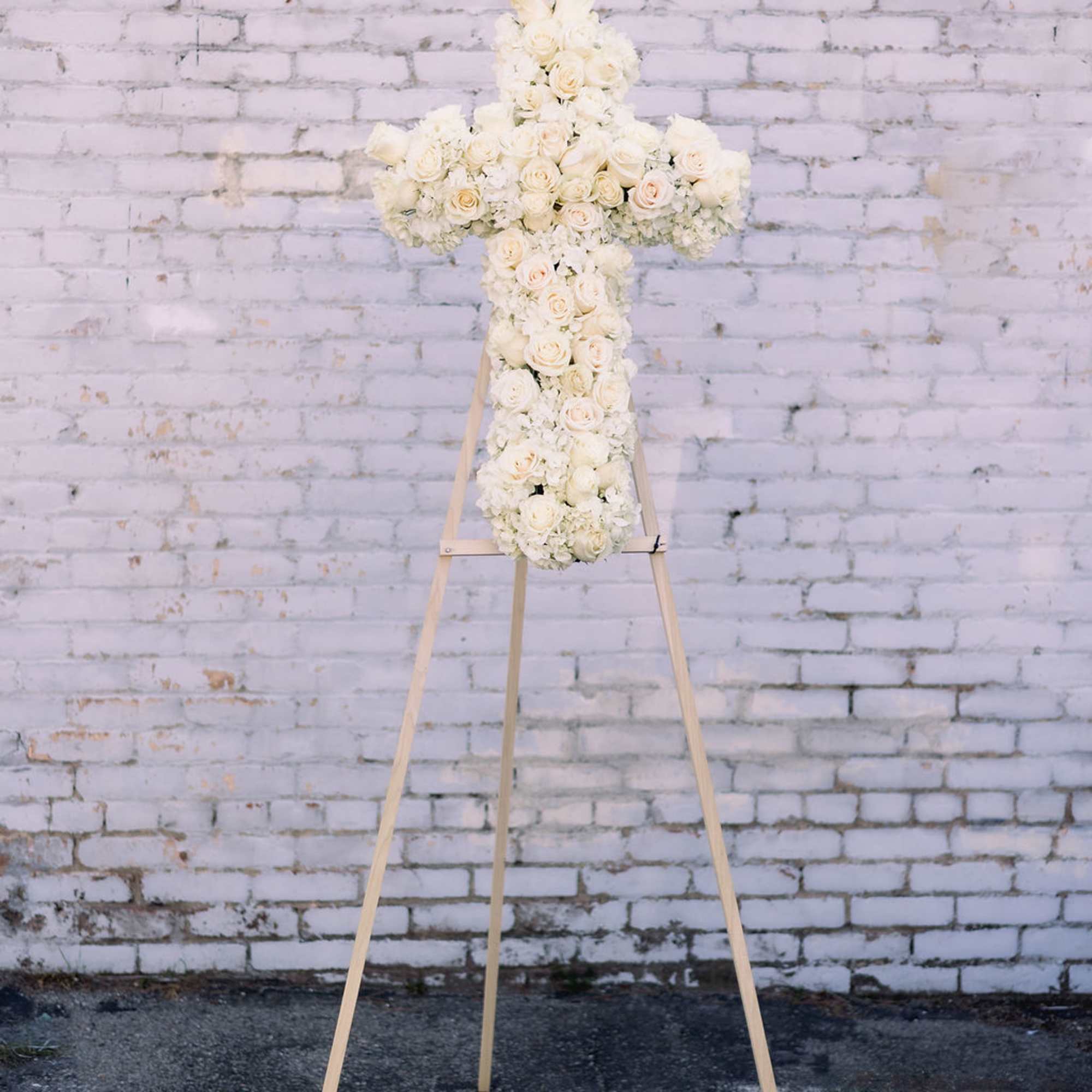 Easel stand cross-shaped spray designed with roses &amp; hydrangea. 
Mounted on a