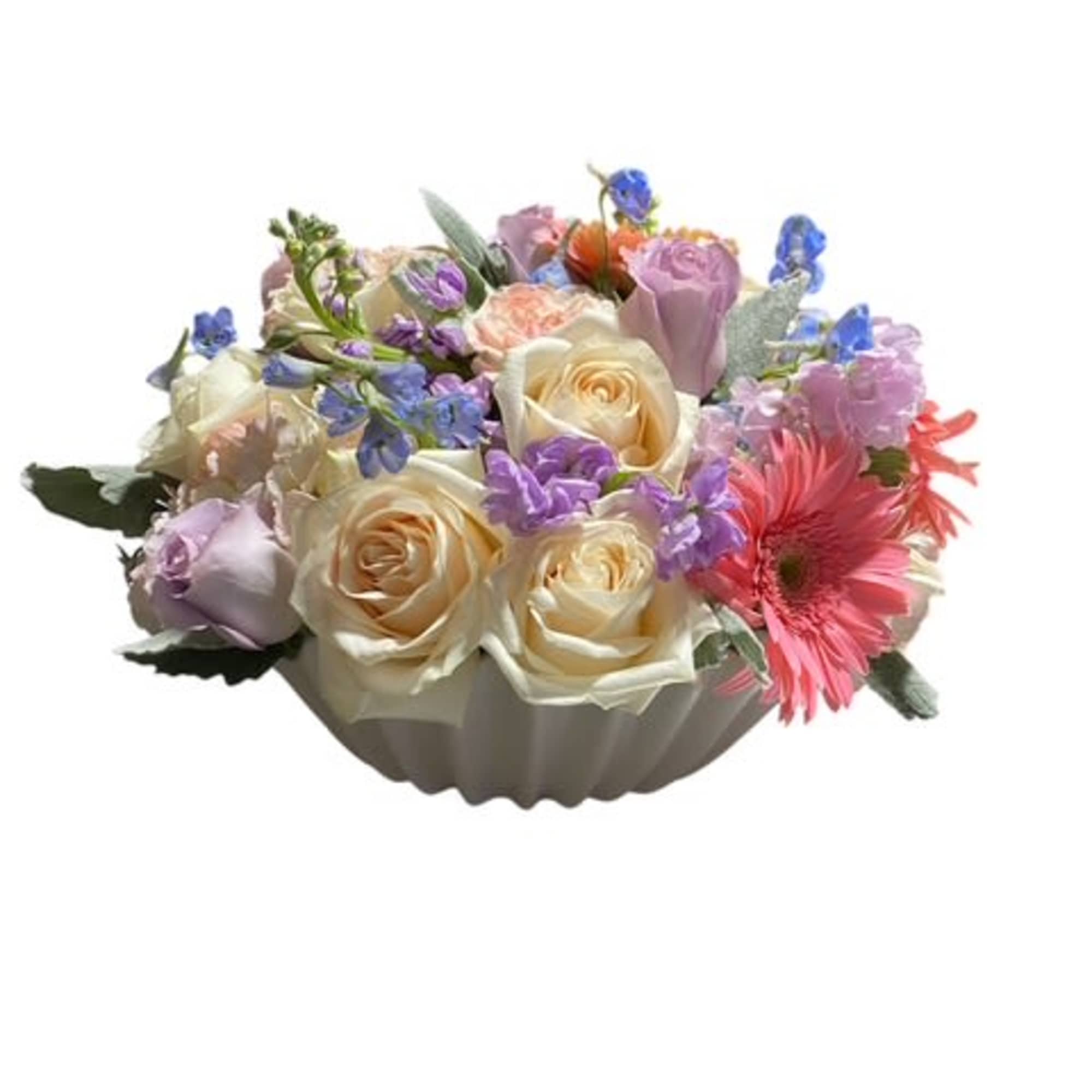 Mixed bouquet of roses, gerbera daisies, and purple flowers in a white bowl vase