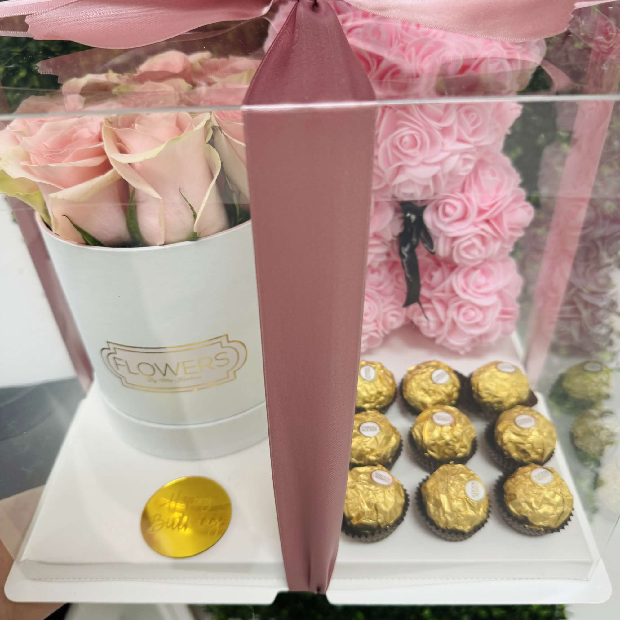 Pink roses in a white box with a pink ribbon and chocolates