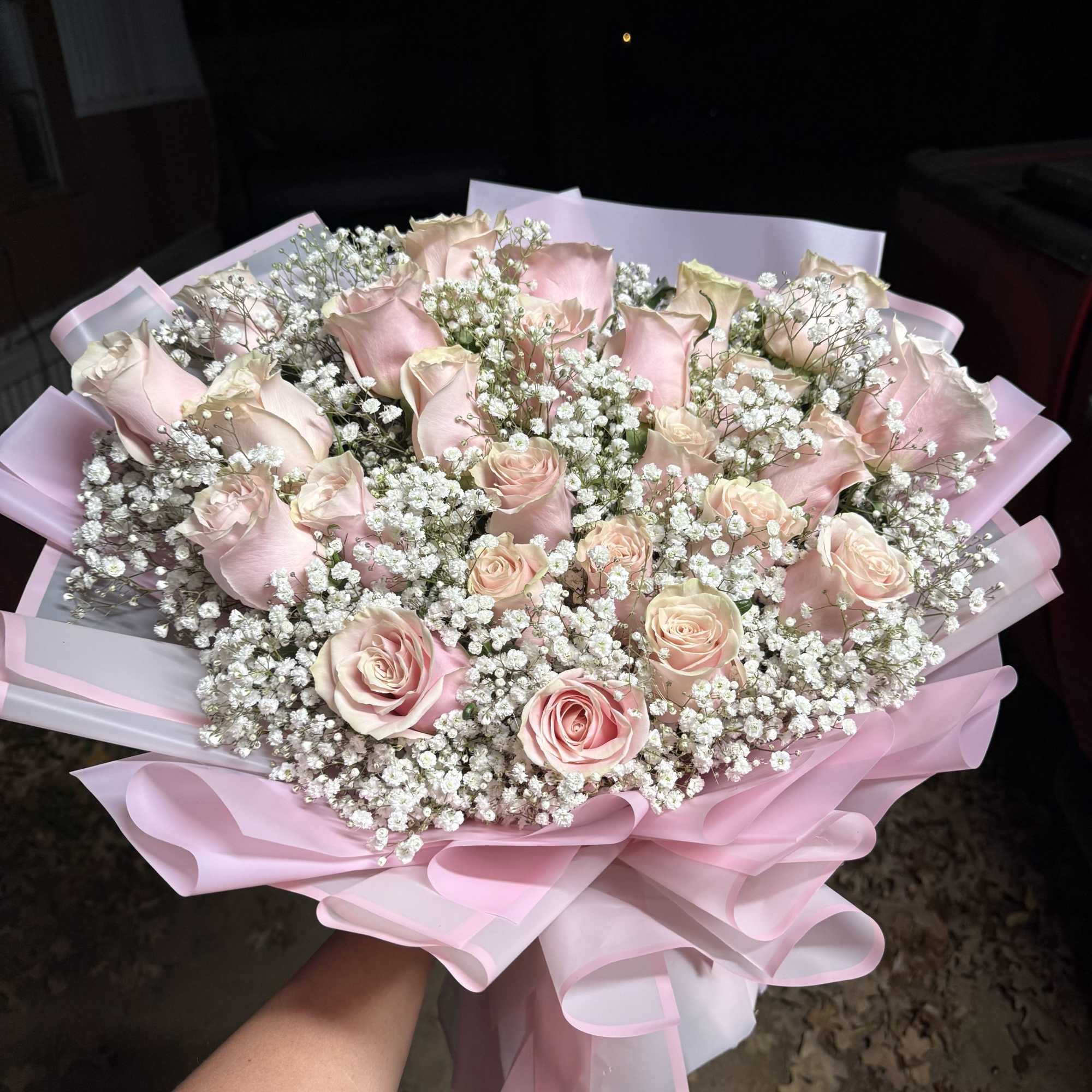Bouquet of pale pink roses with white baby's breath wrapped in pink paper