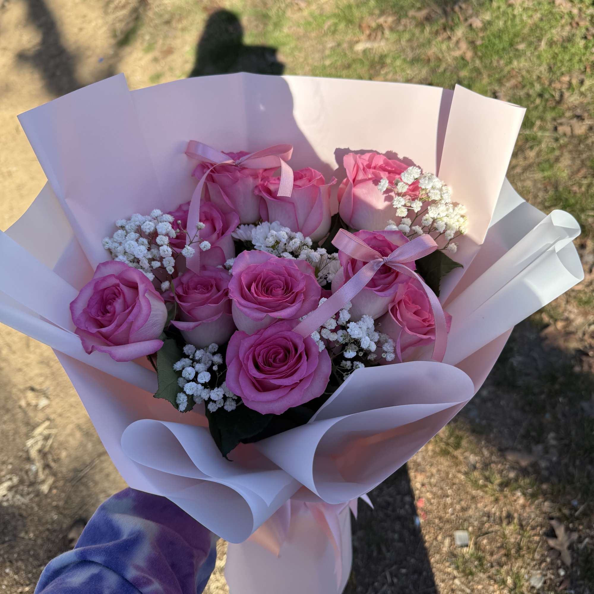Pink rose bouquet wrapped in pale paper with ribbon
