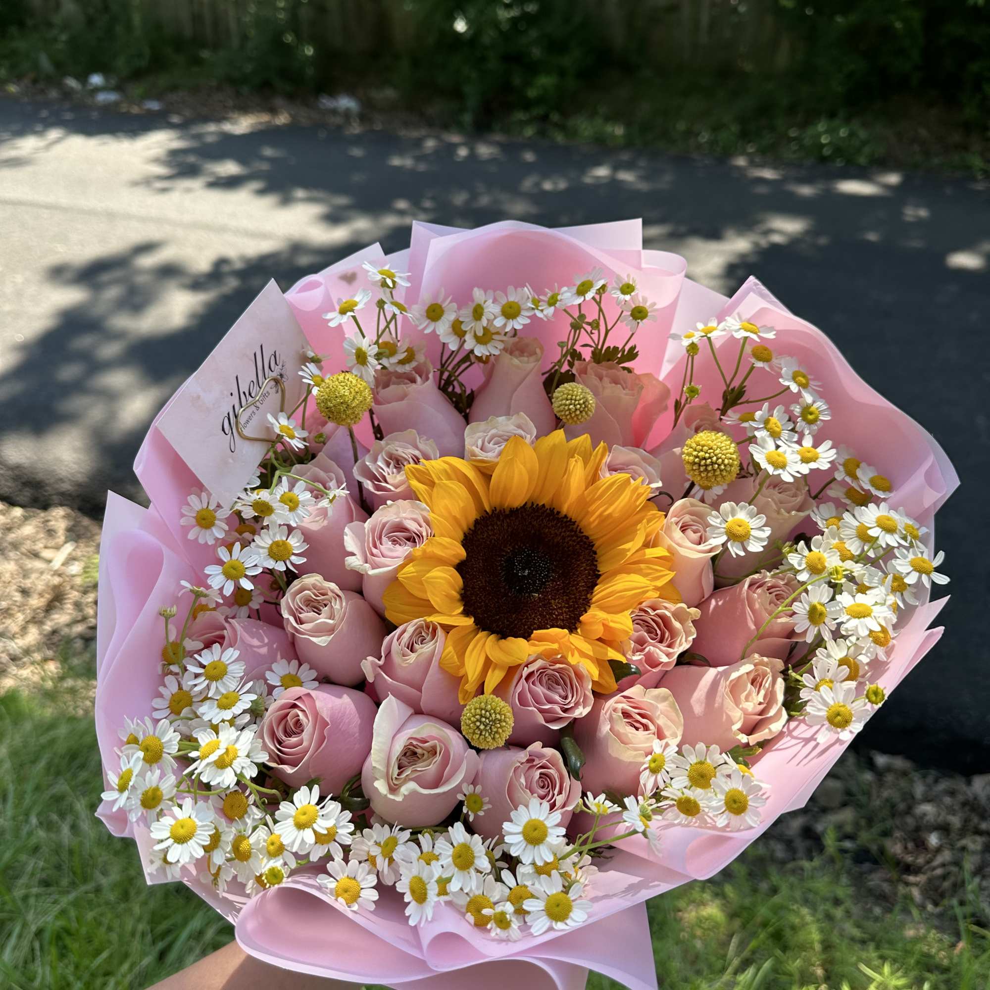 Pink rose bouquet with a sunflower center and white daisies