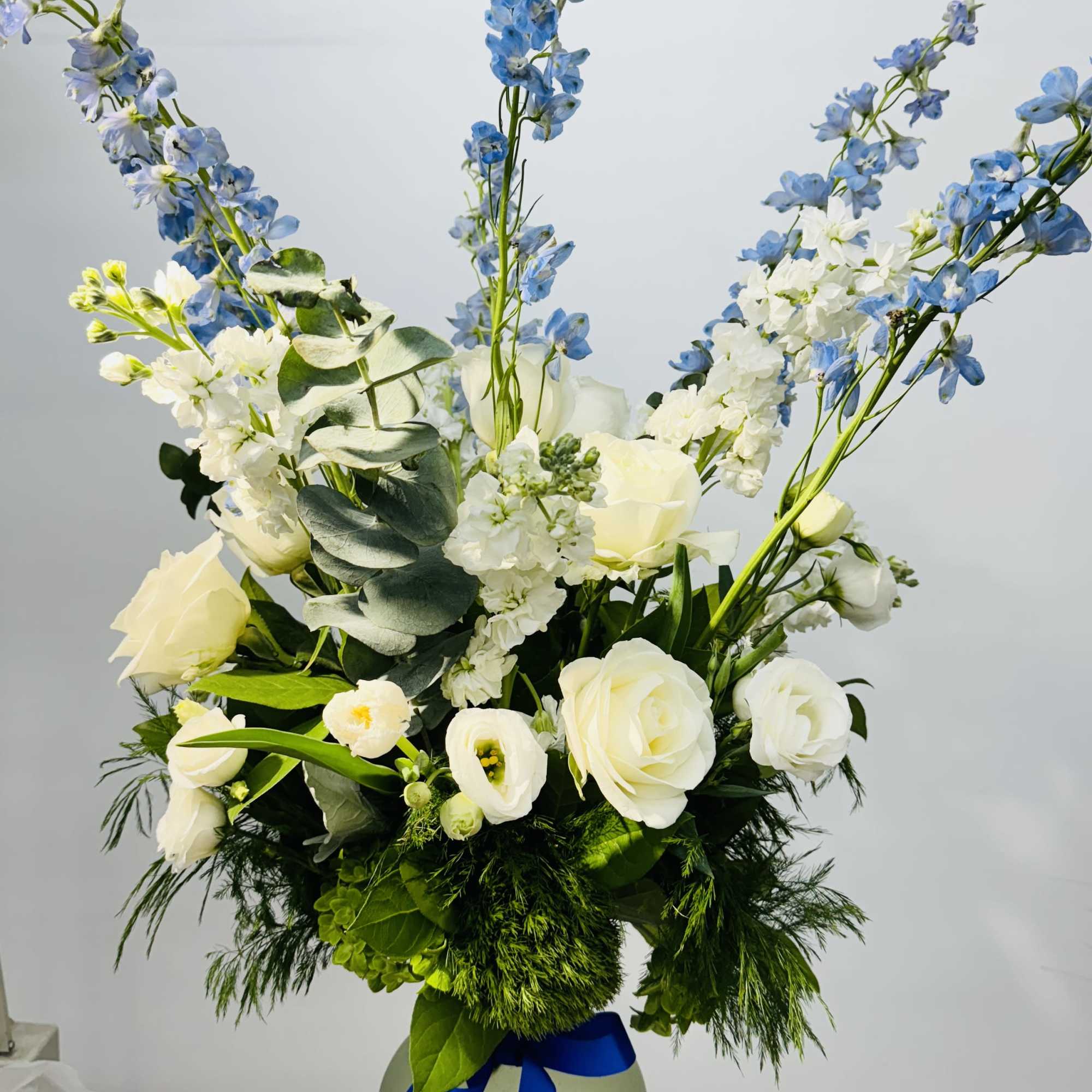 A blue and white arrangement featuring roses, tulips, and delphinium. Send this