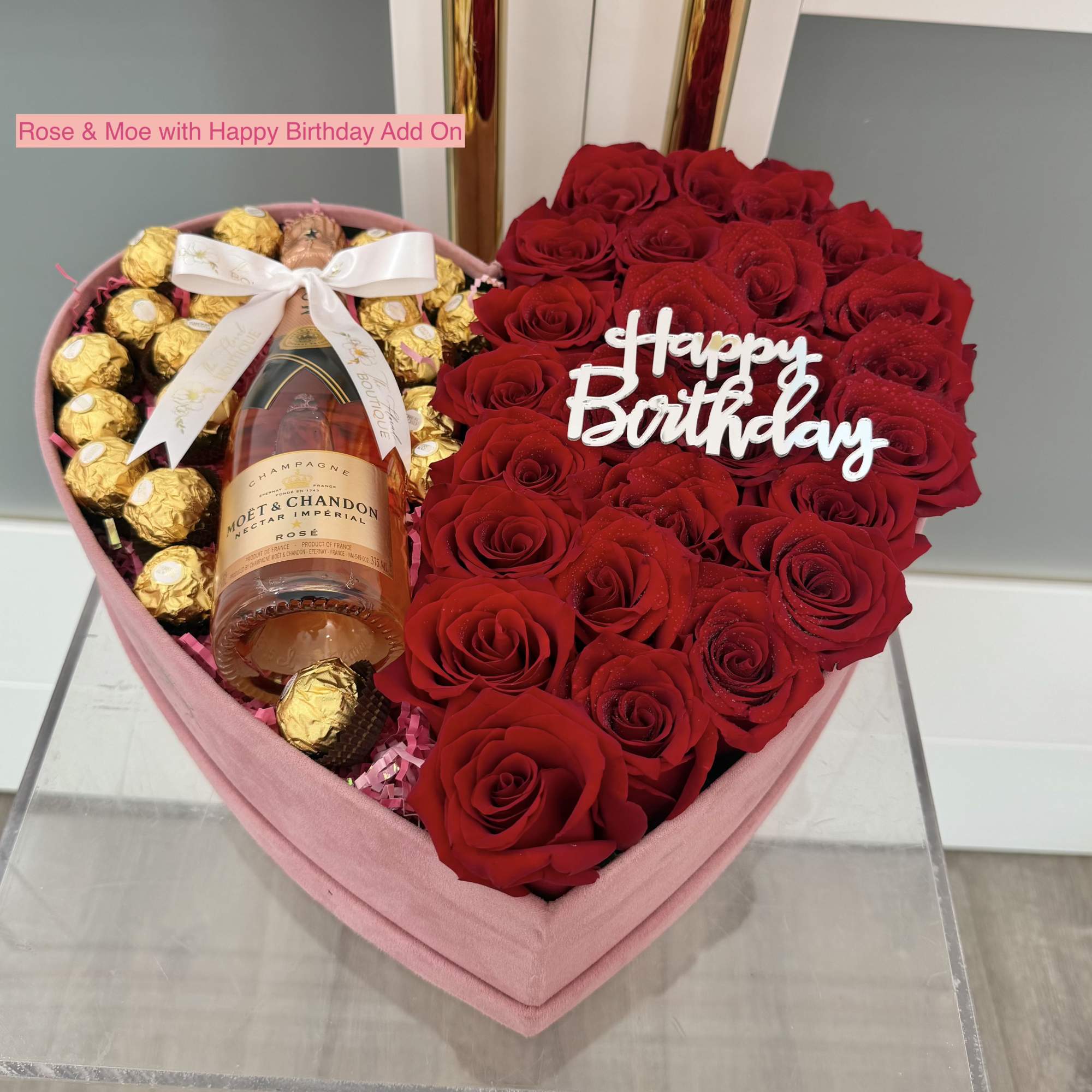 Heart-shaped box of red roses with chocolates and a champagne bottle