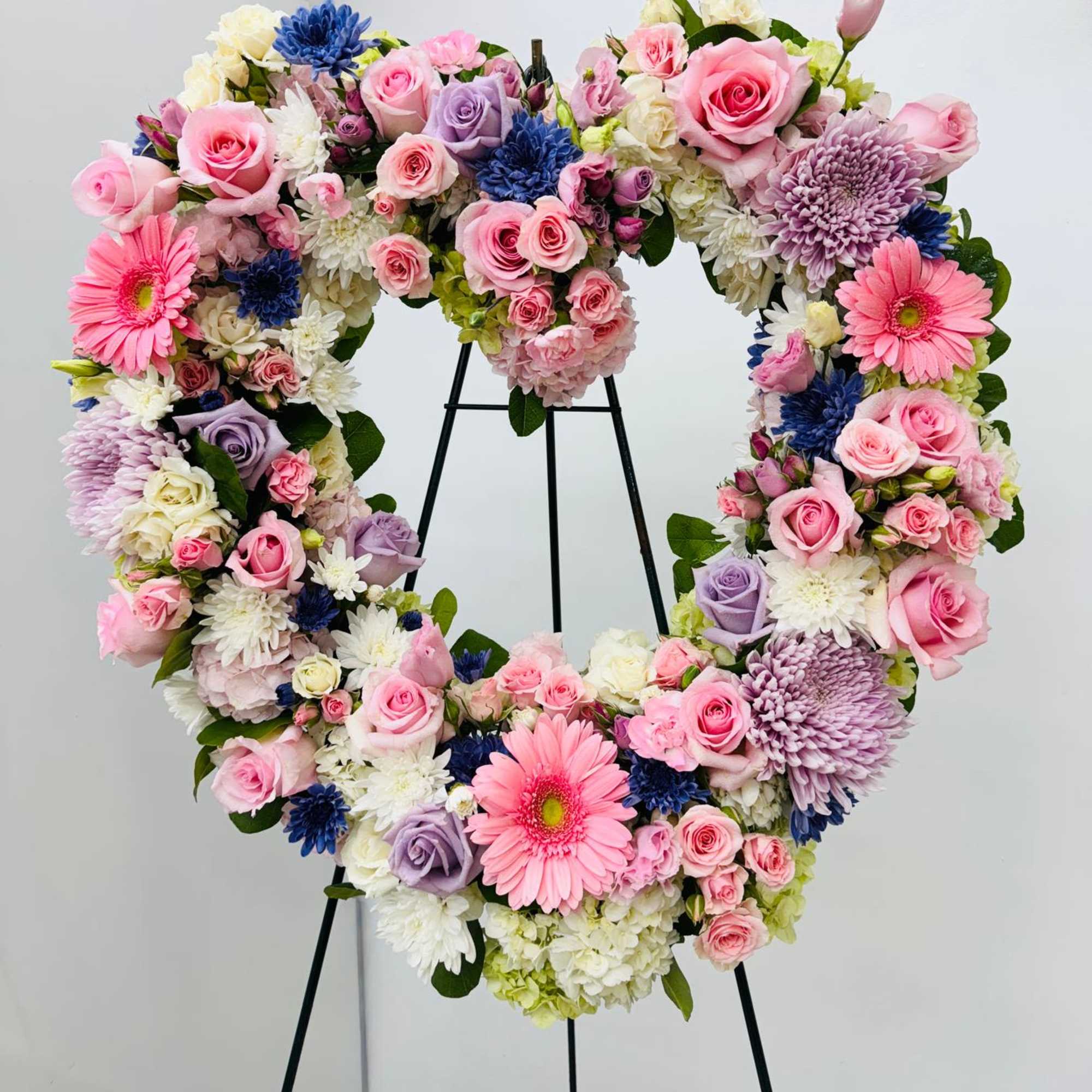 Heart-shaped floral wreath with pink, white, lavender, and blue blooms