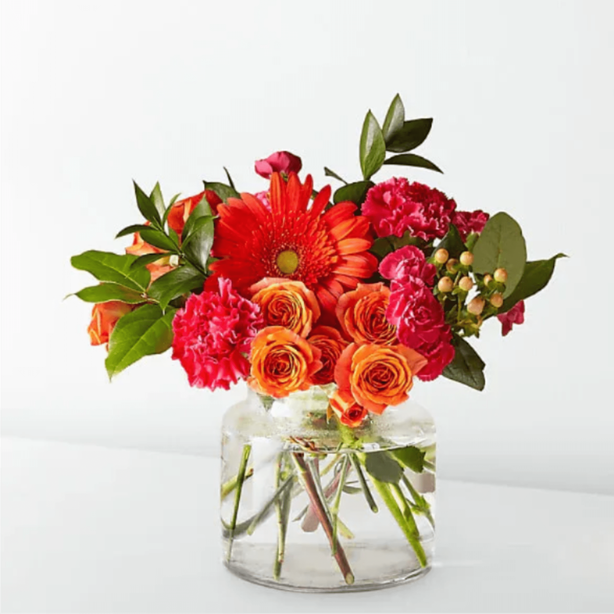 Orange and pink mixed bouquet in a clear glass vase