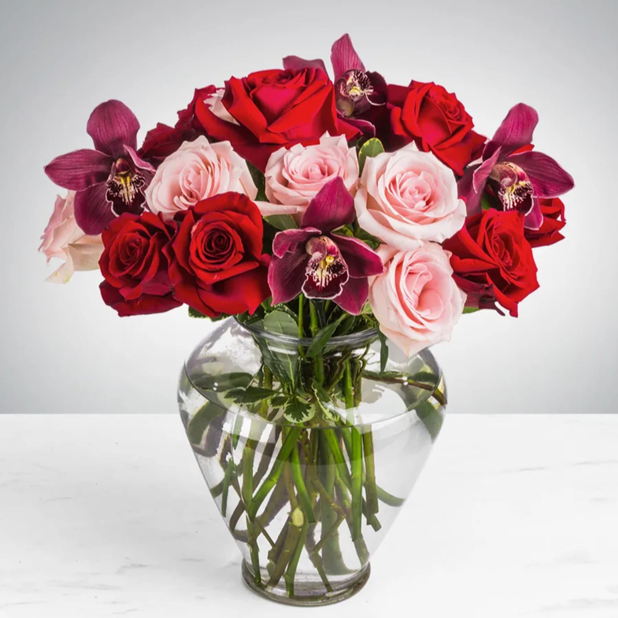 This arrangement includes purple cymbidium orchids, red roses, &amp; pink roses. Truly