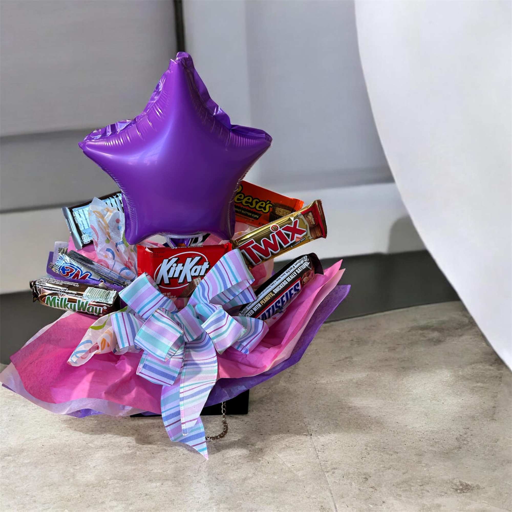 Candy bouquet with a purple star balloon and assorted chocolate bars