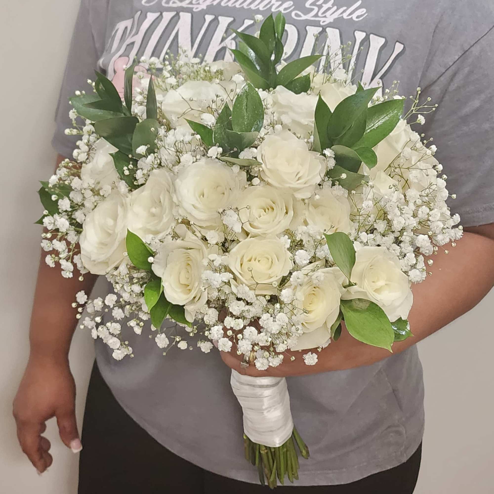 White roses complemented by delicate baby&rsquo;s breath and lush greenery. Wrapped with