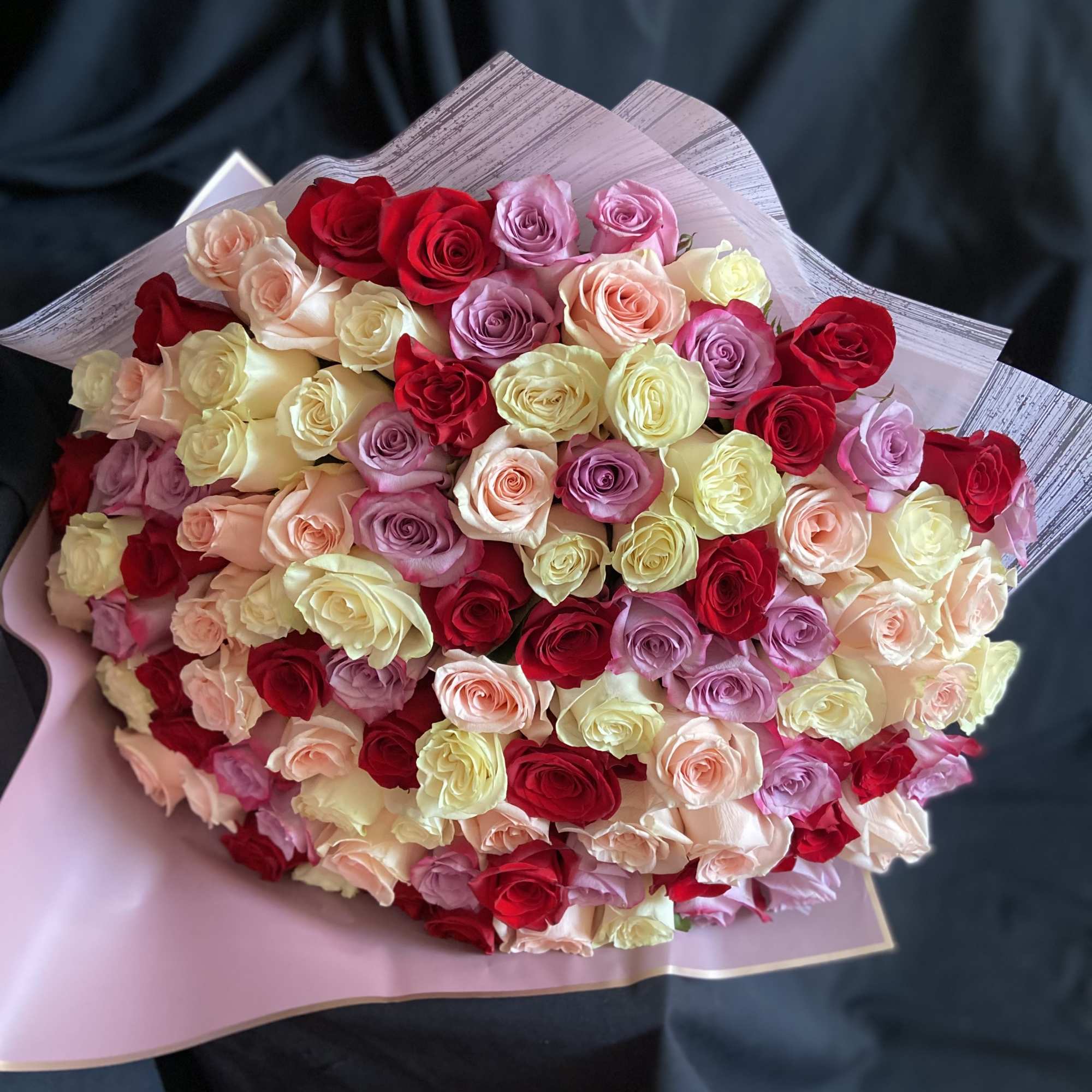Large bouquet of multicolored roses wrapped in pink paper