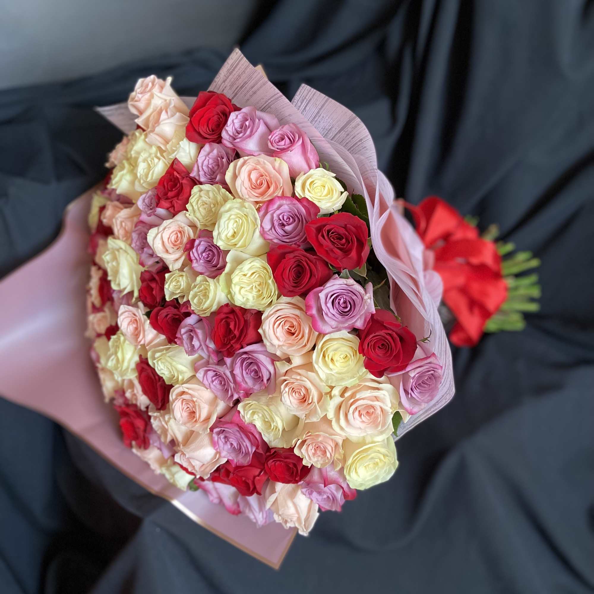 Bouquet of multicolored roses wrapped in pink paper