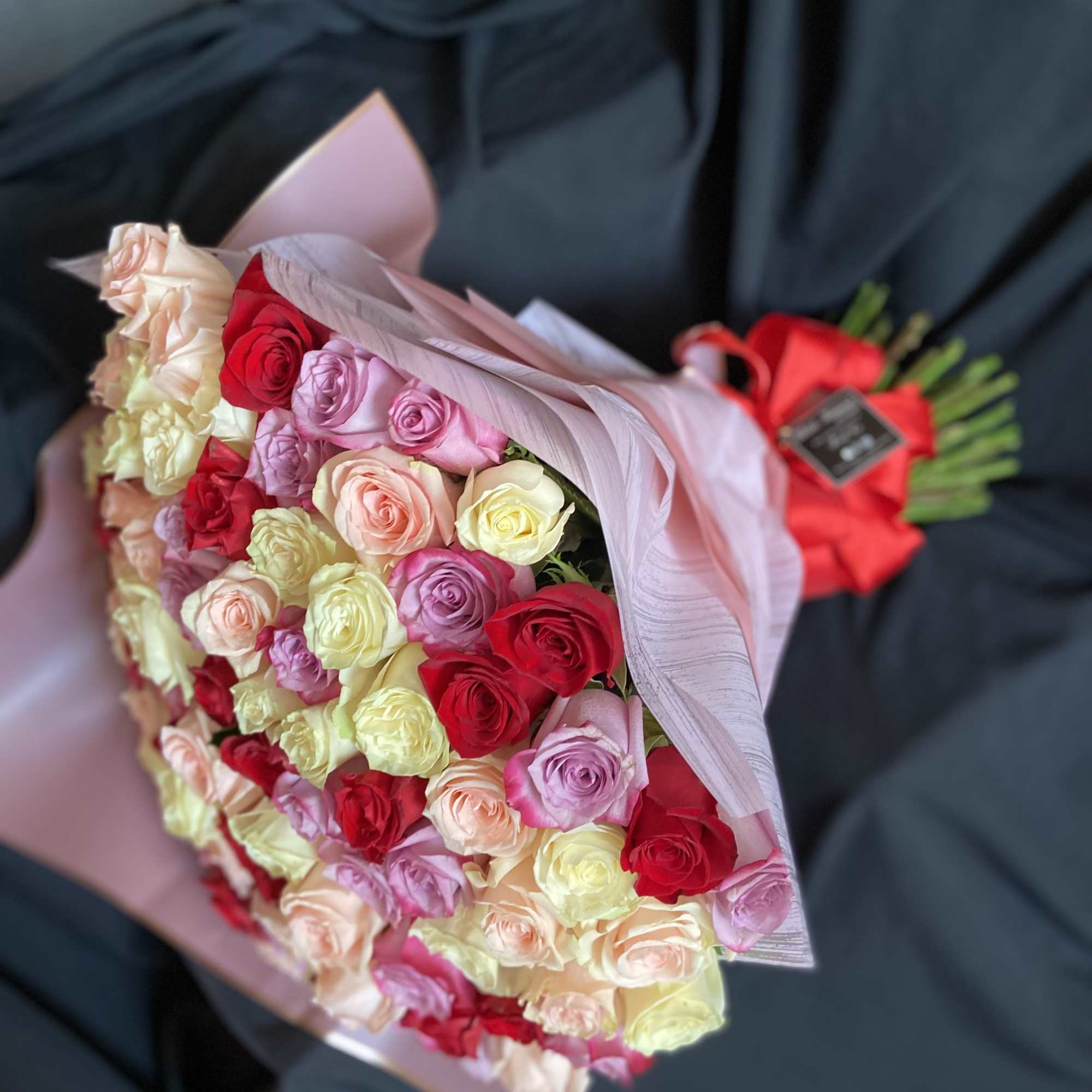 Bouquet of multicolored roses wrapped in pale pink paper