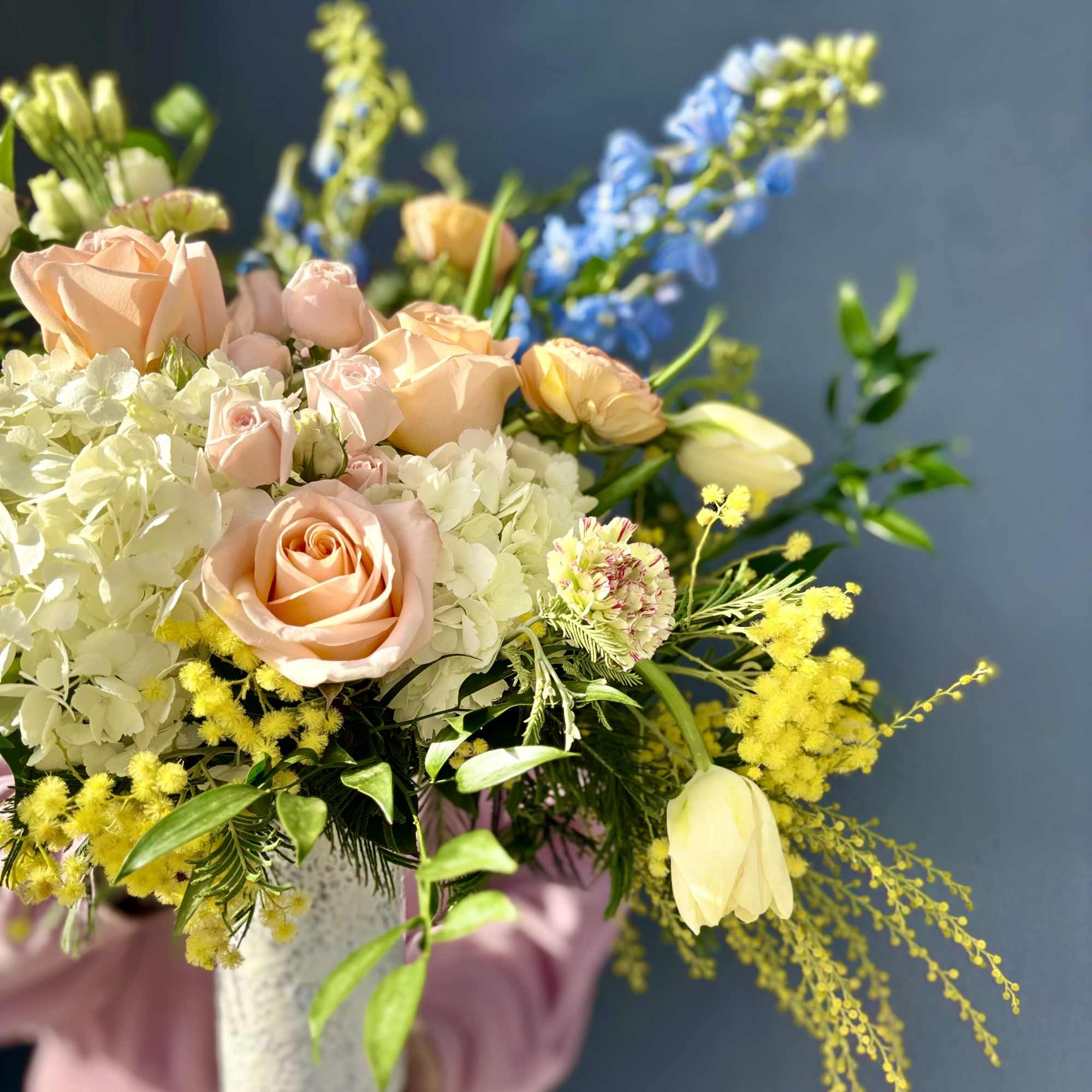 A bright and cheery seasonal arrangement. Vibrant and fragrant Mimosa compliment calming
