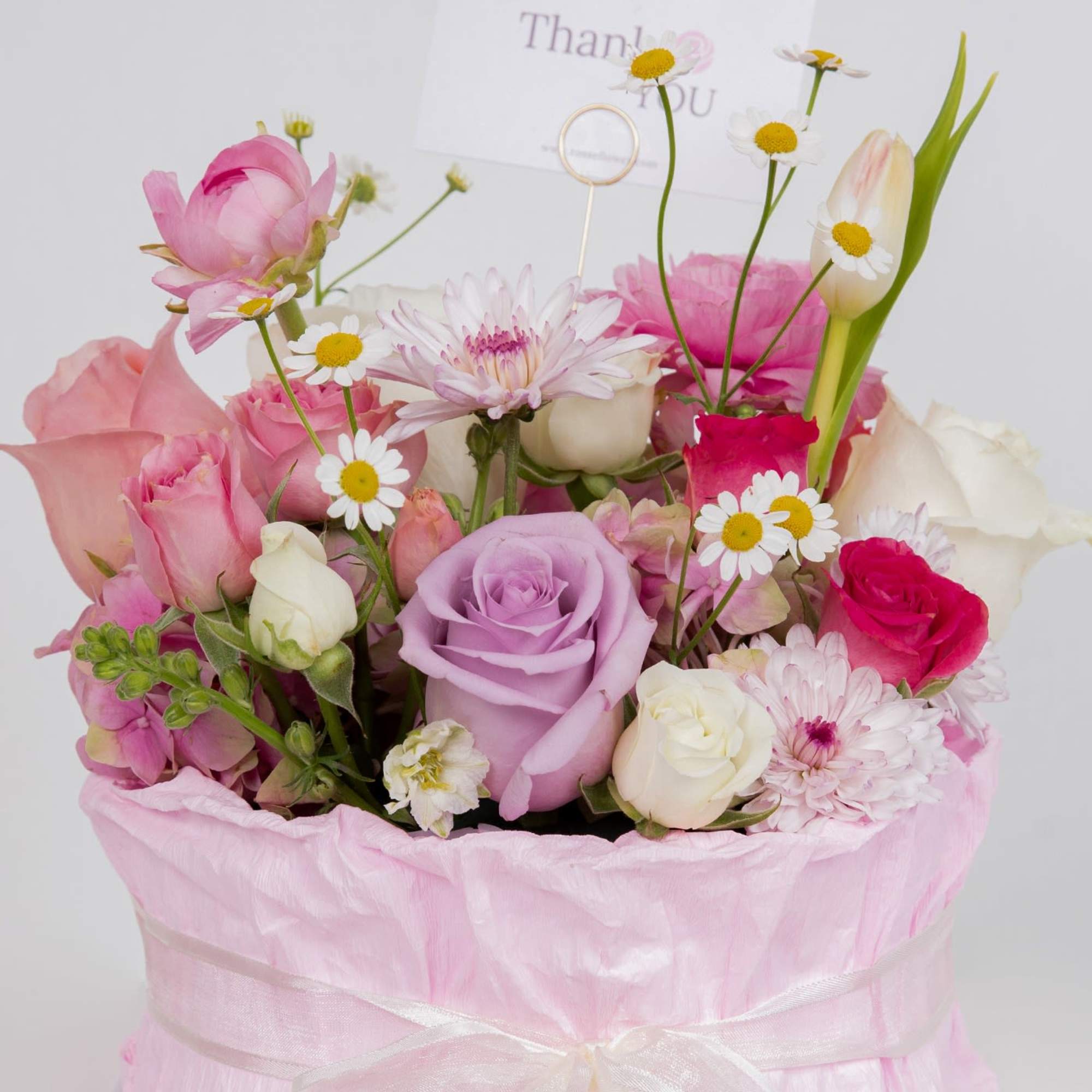 A cake-inspired floral design featuring roses and seasonal blooms in soft pink