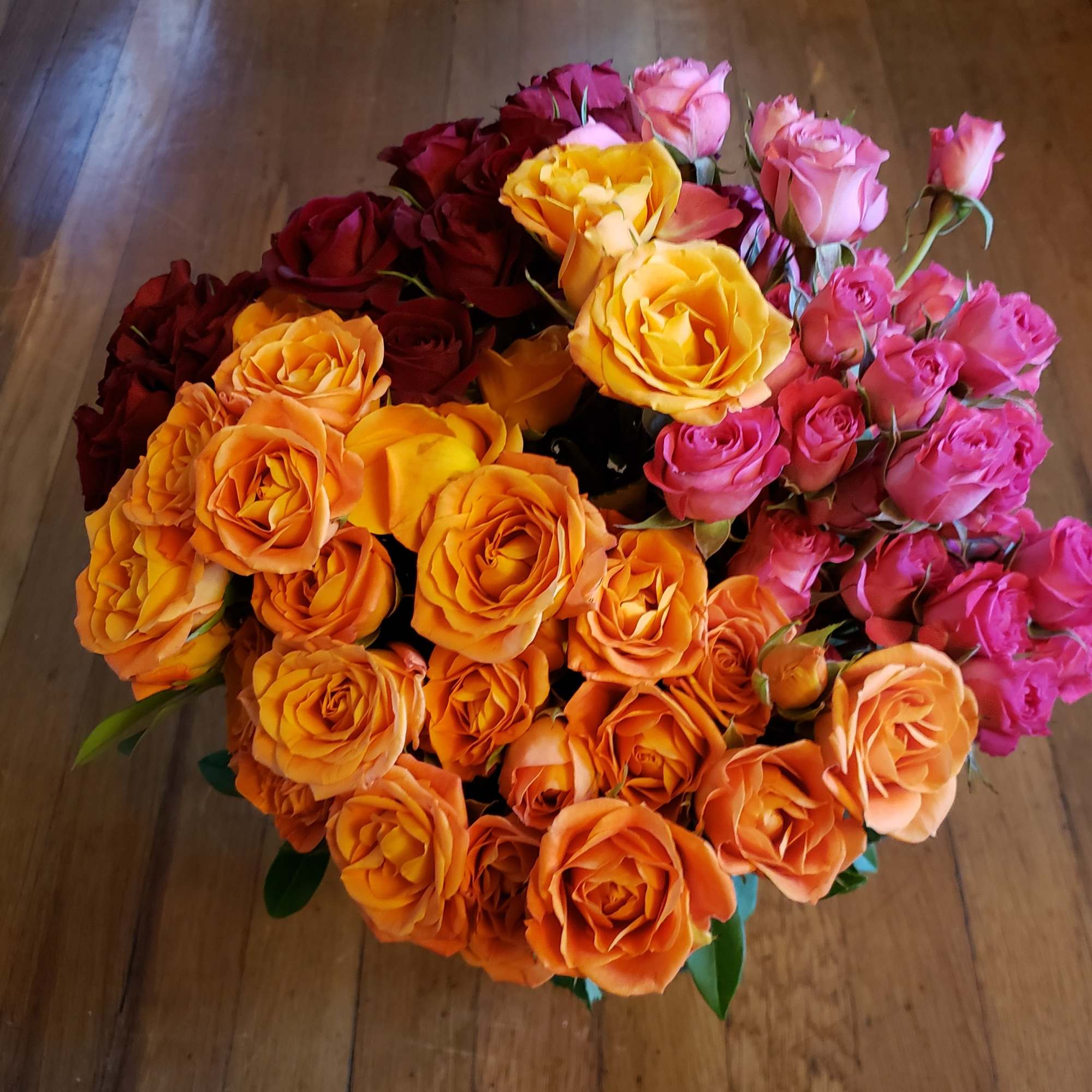 A large bouquet of roses in orange, yellow, red, and pink.