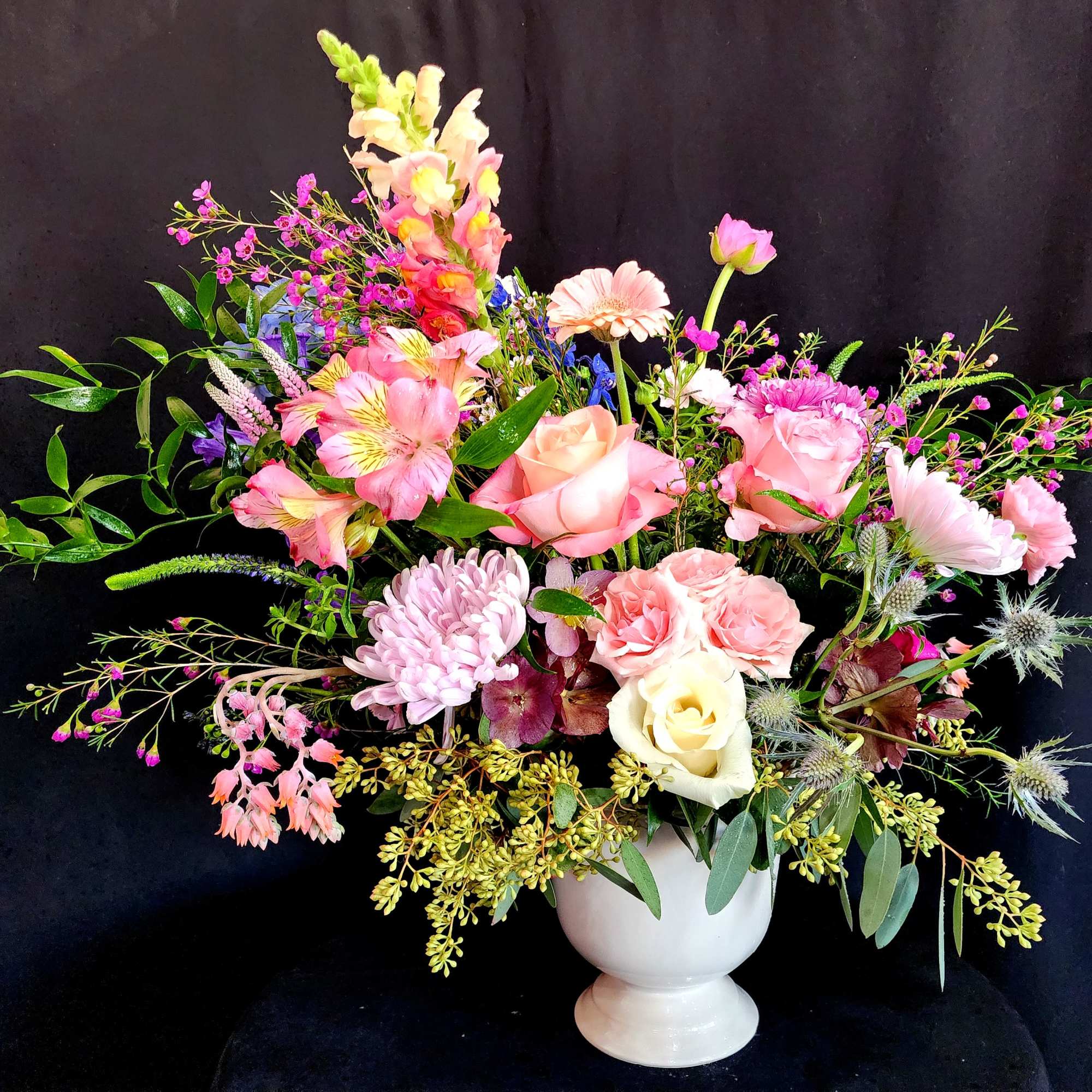 Mixed pink and peach floral arrangement in a white vase