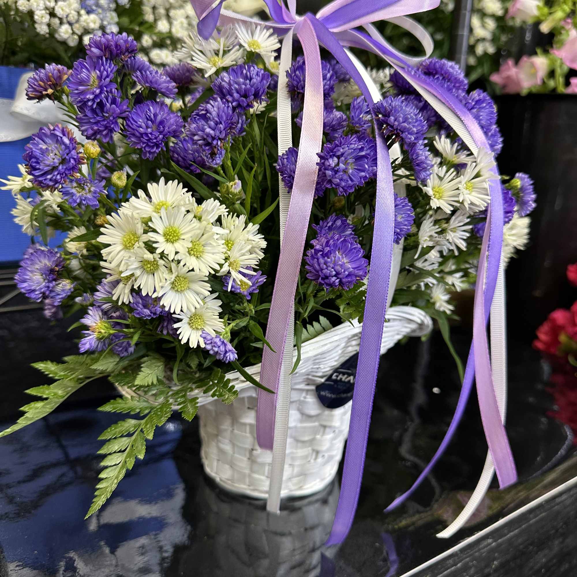 Purple and white fresh cut flowers in a white basket