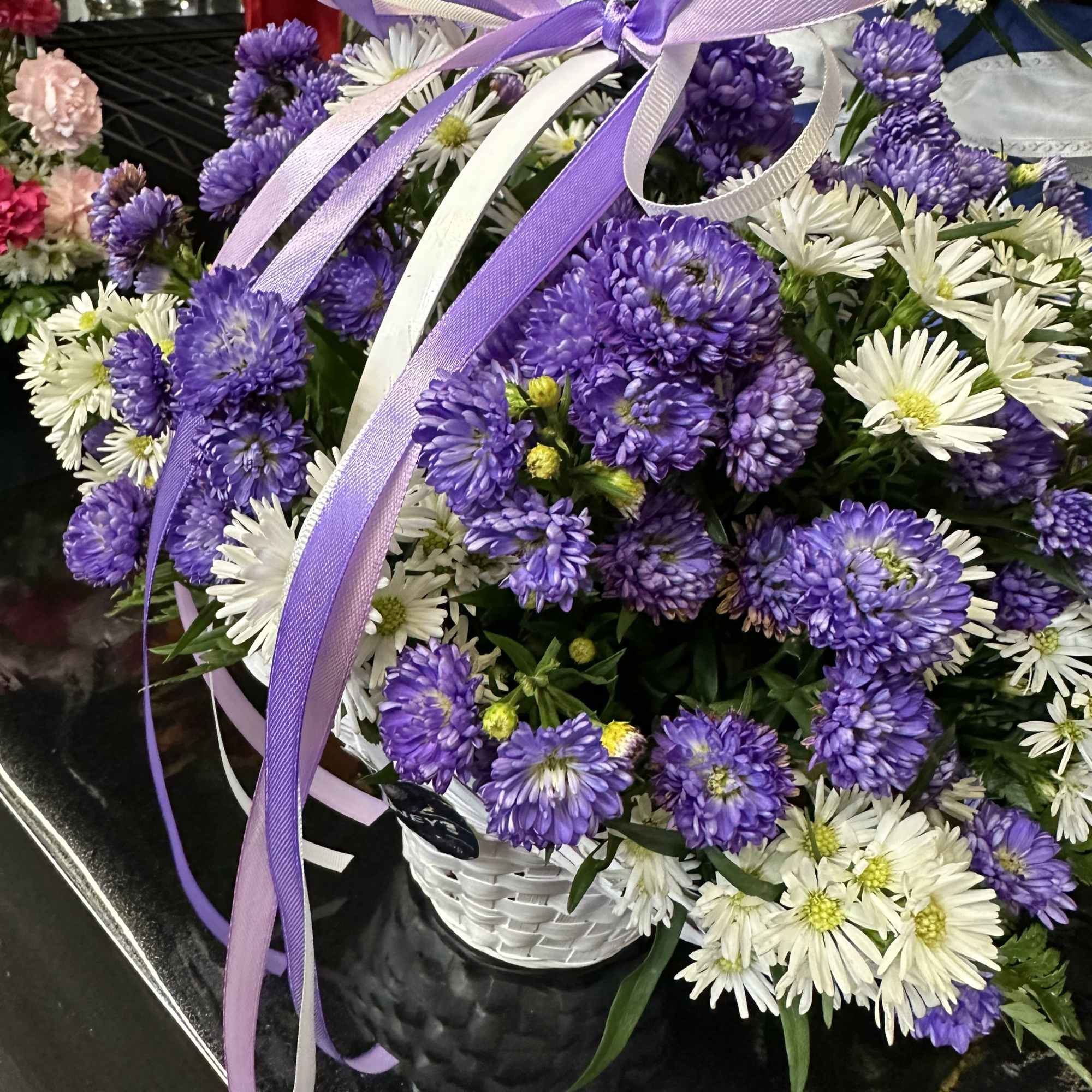 Purple and white fresh cut flowers in a white basket