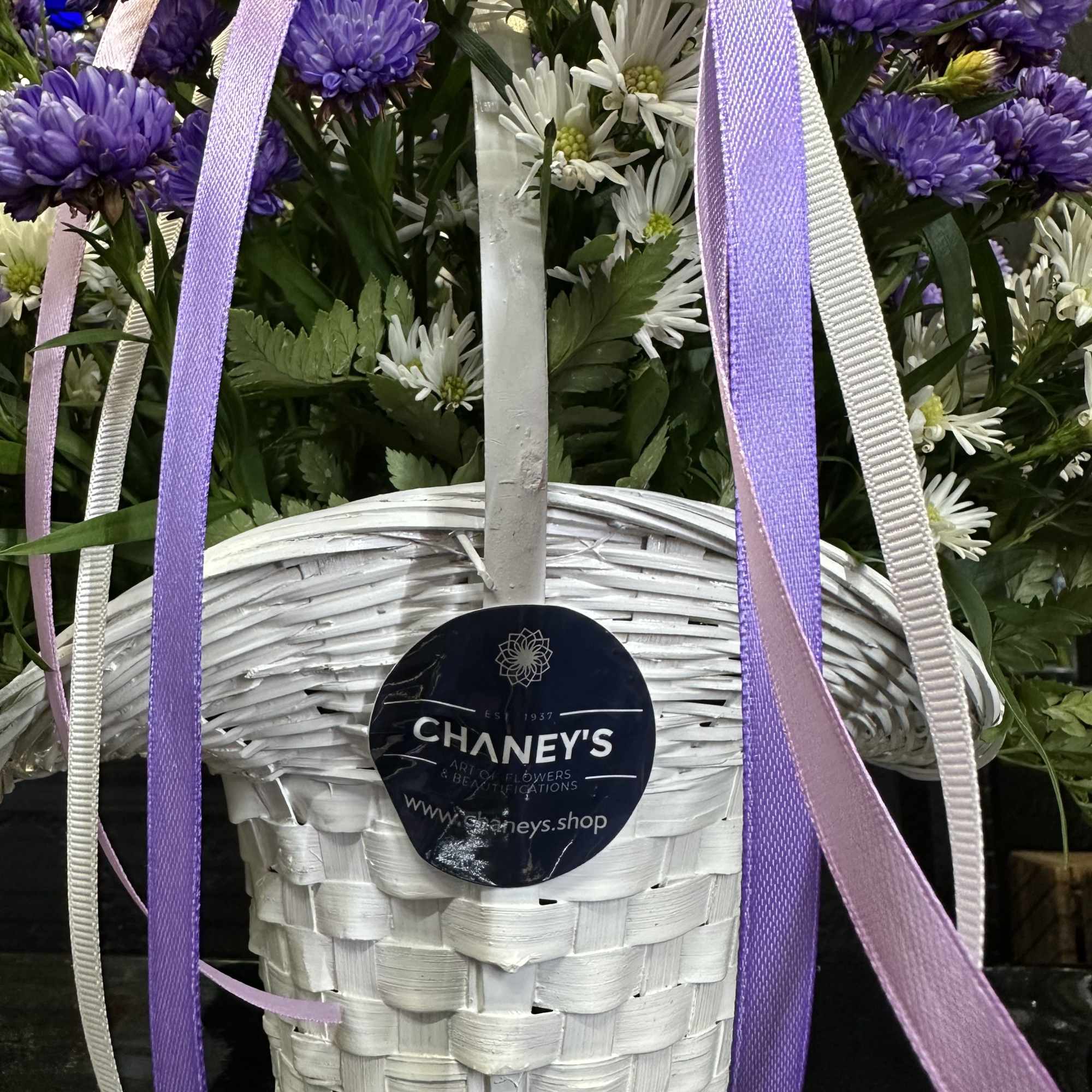 Purple and white fresh cut flowers in a white basket