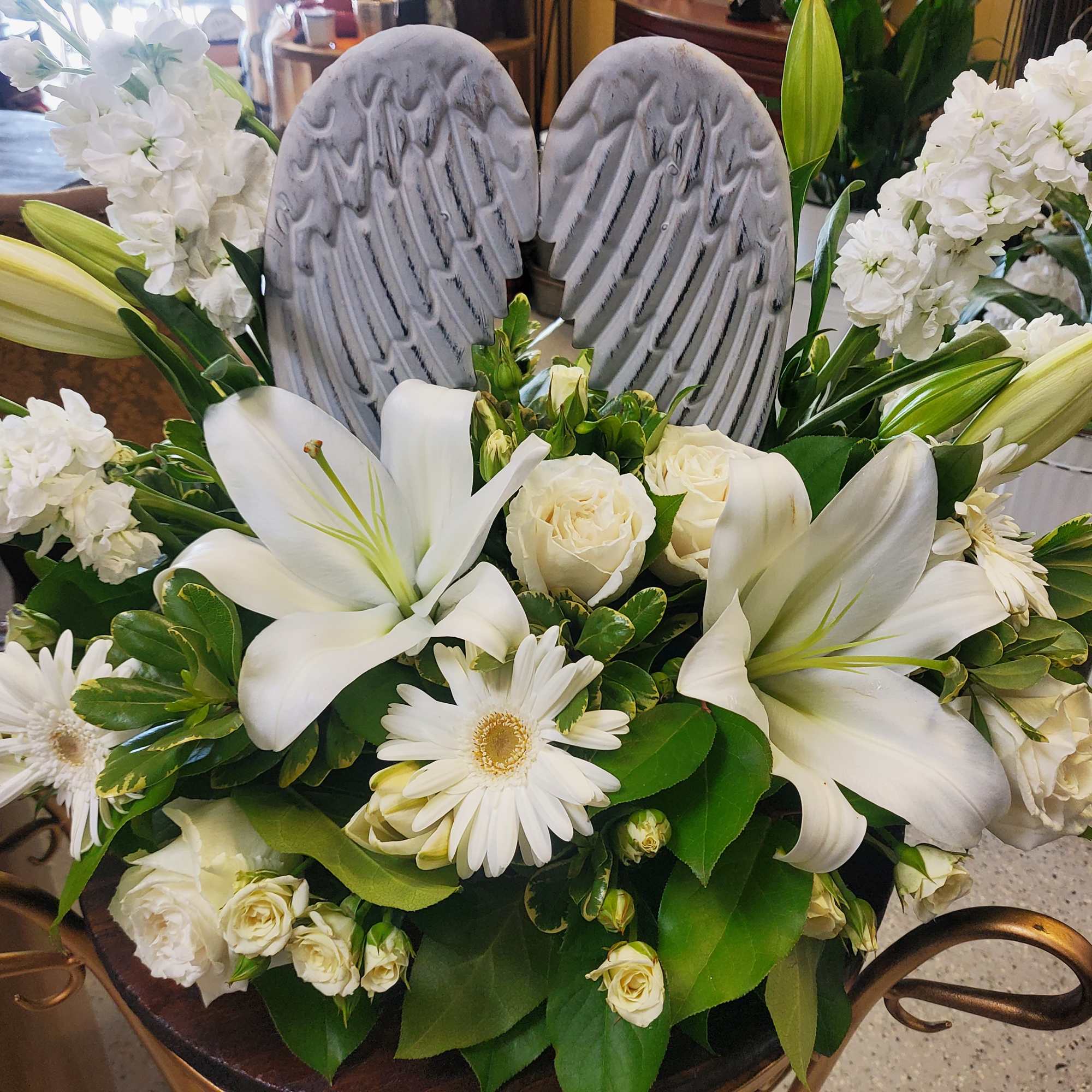 This tasteful design of roses, lilies, stock, and white mums with a