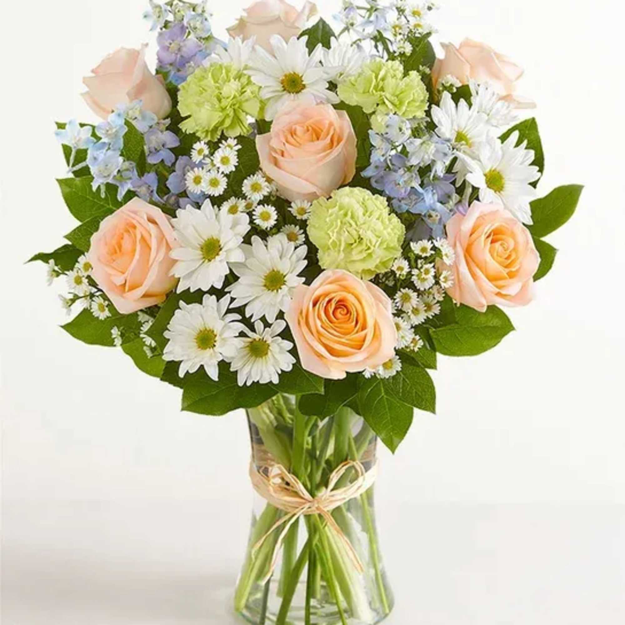 Bouquet of peach roses, white daisies, and pastel filler flowers in a glass vase