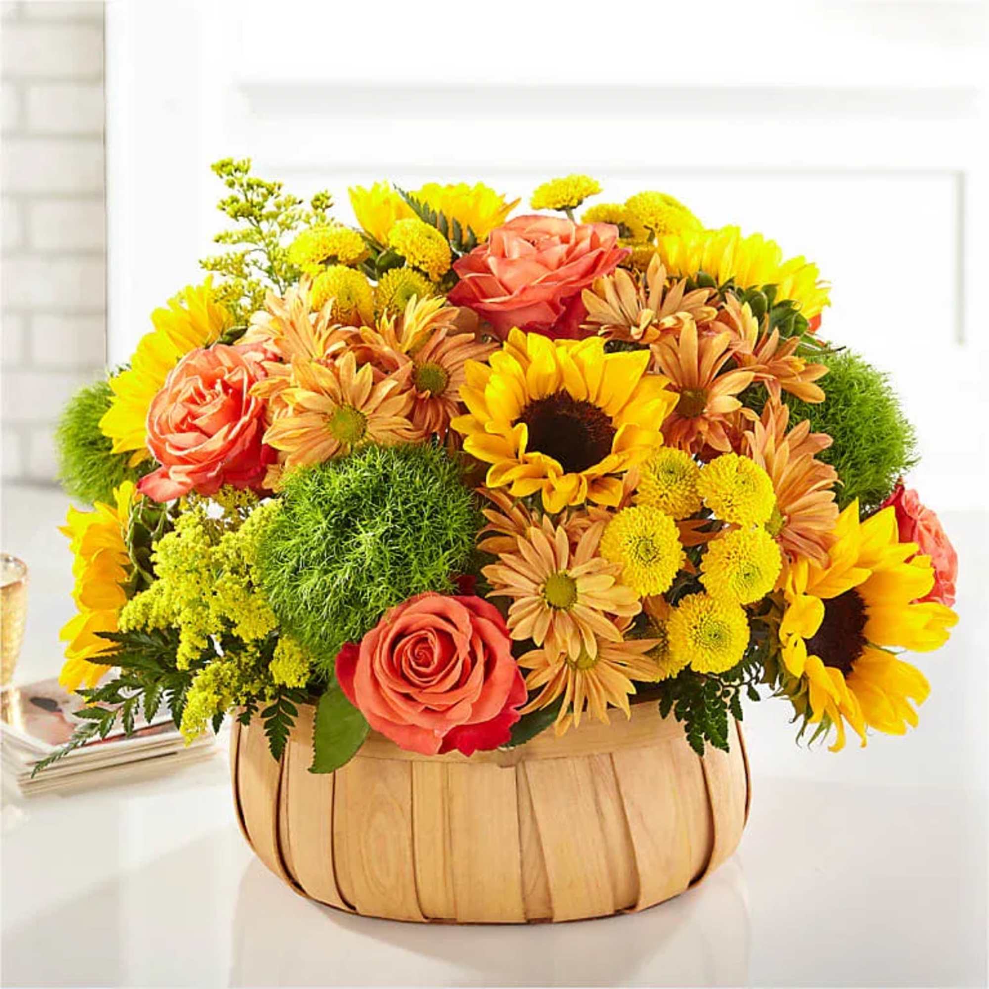 Basket arrangement of sunflowers, roses, and mums in yellow, orange, and pink