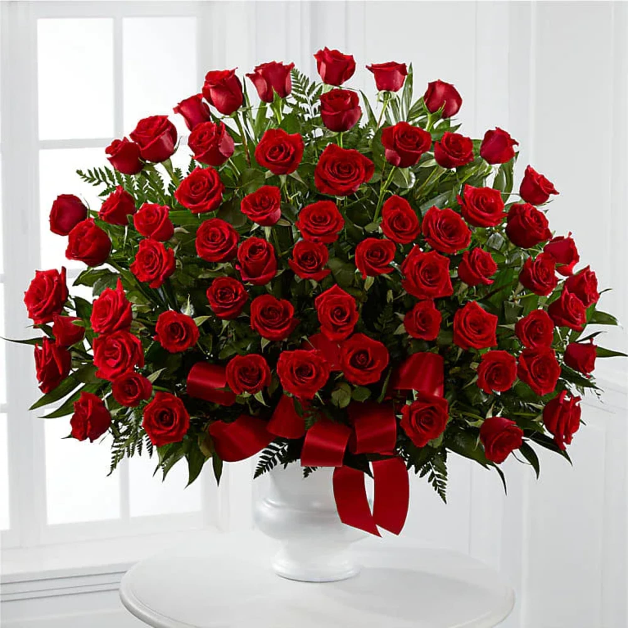 Large bouquet of red roses in a white vase with a red ribbon