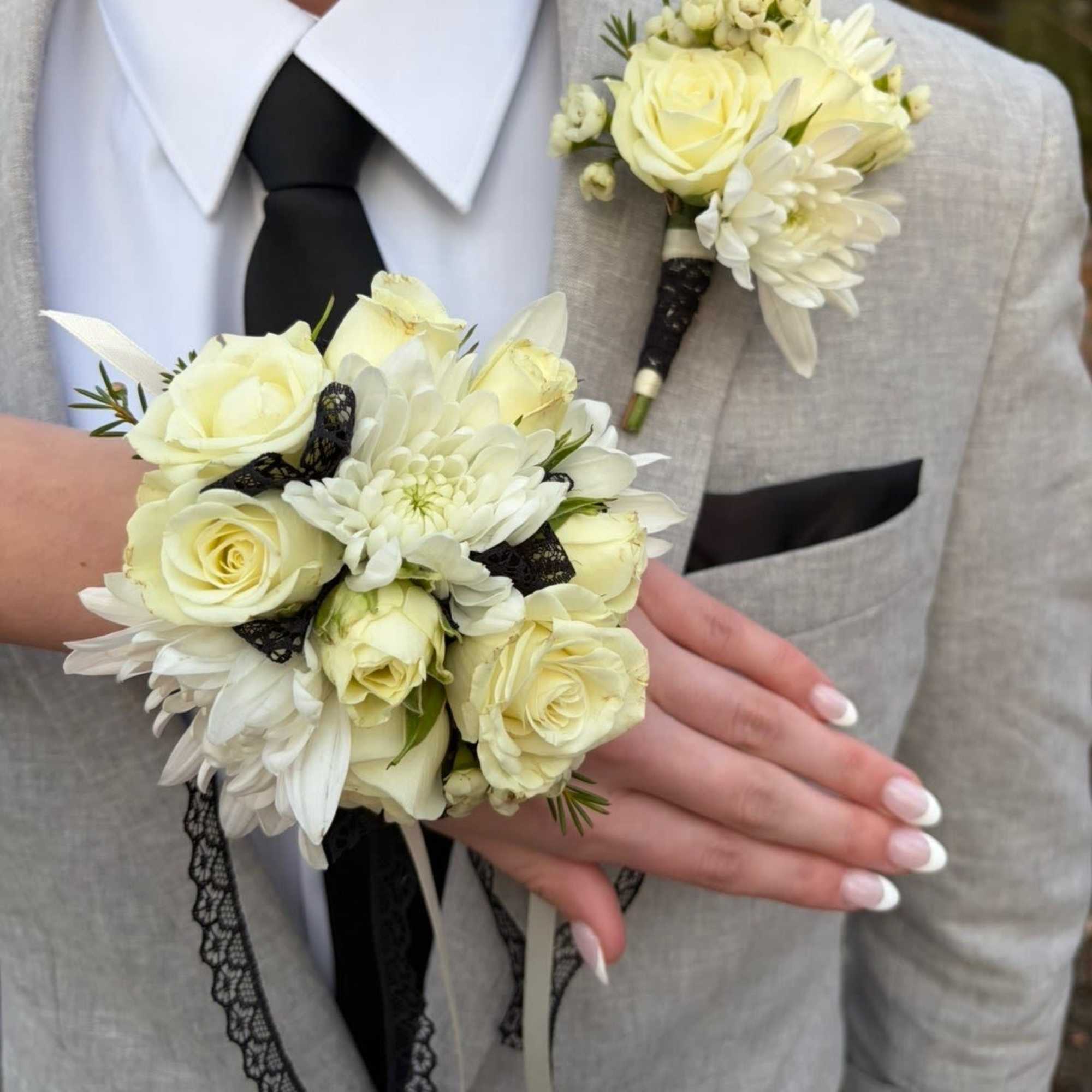 White rose boutonniere and matching wrist corsage on a light suit