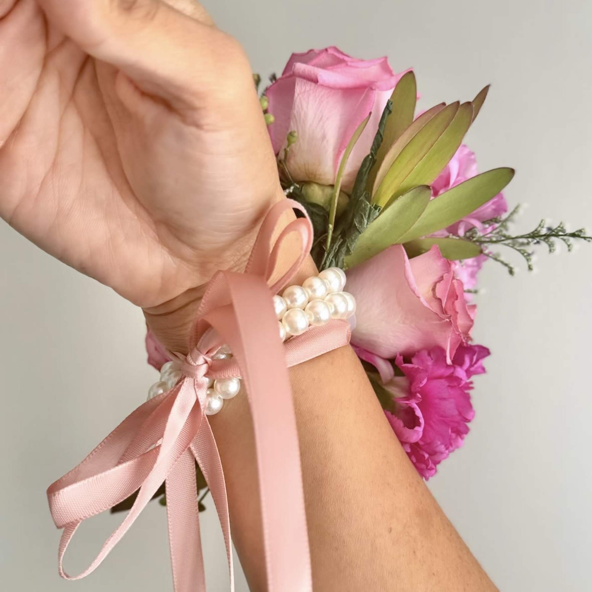 Pink rose wrist corsage with ribbon and pearl accents