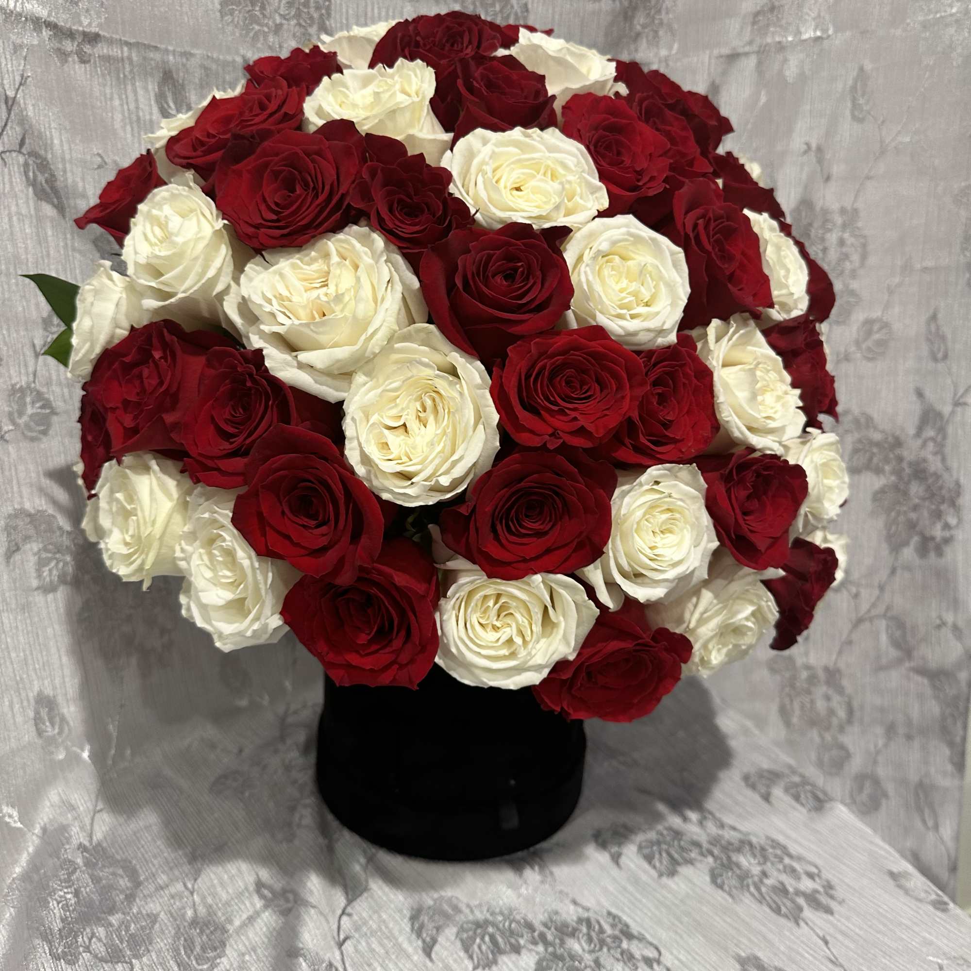 Red and white rose bouquet in a black vase