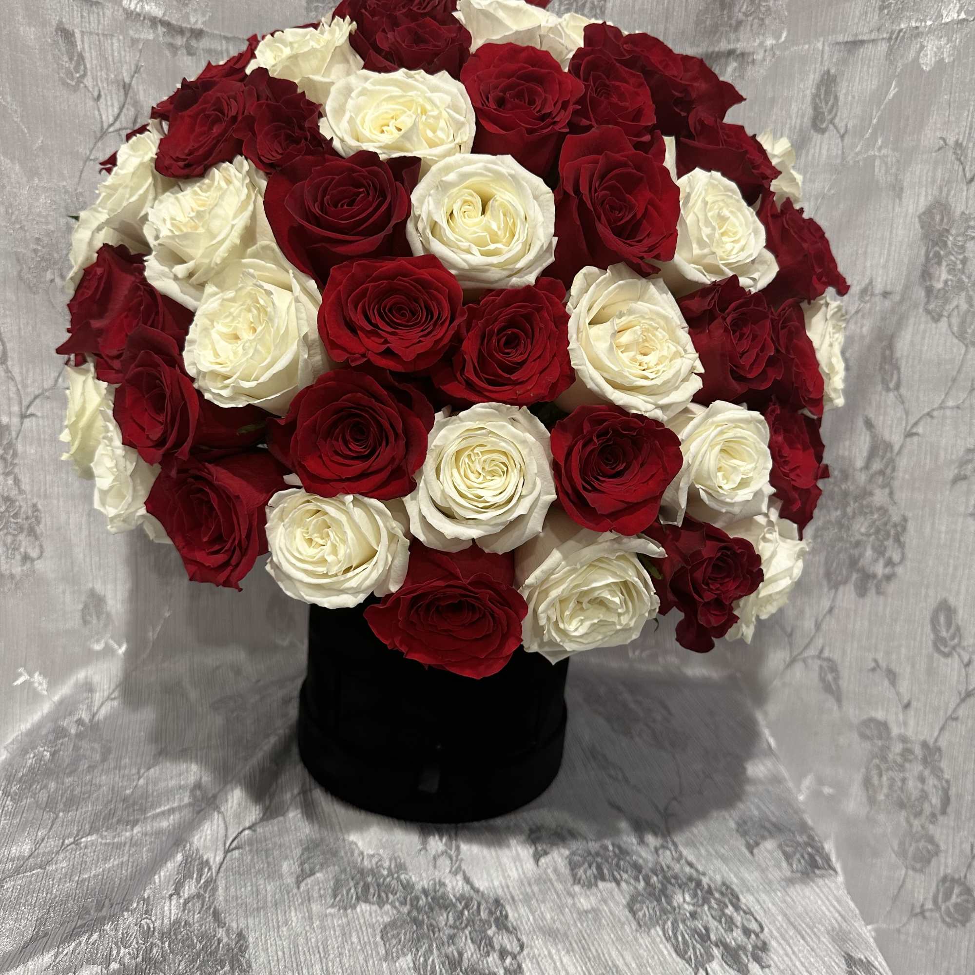 Red and white rose arrangement in a black vase