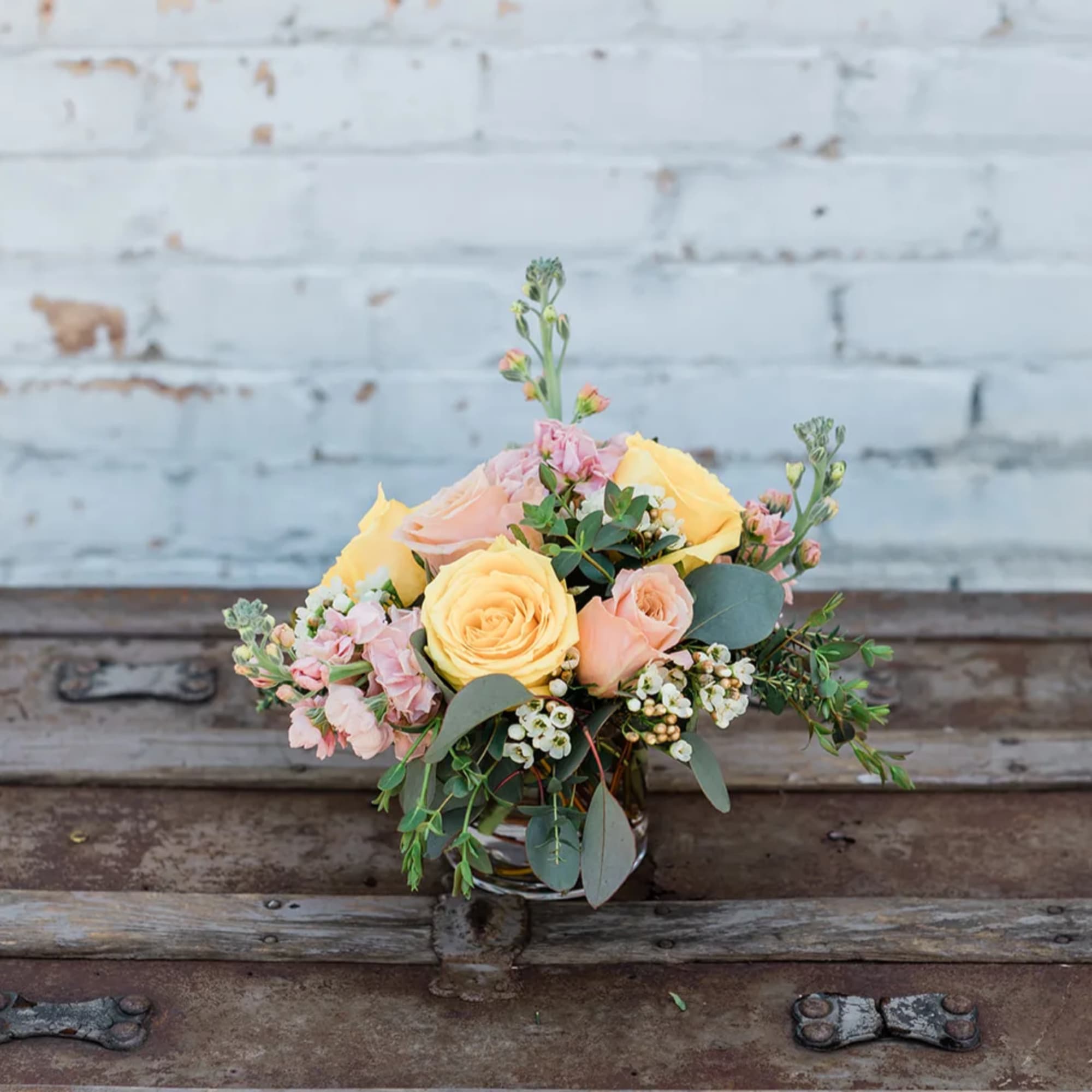 Bouquet of yellow and peach roses with pink flowers in a glass vase