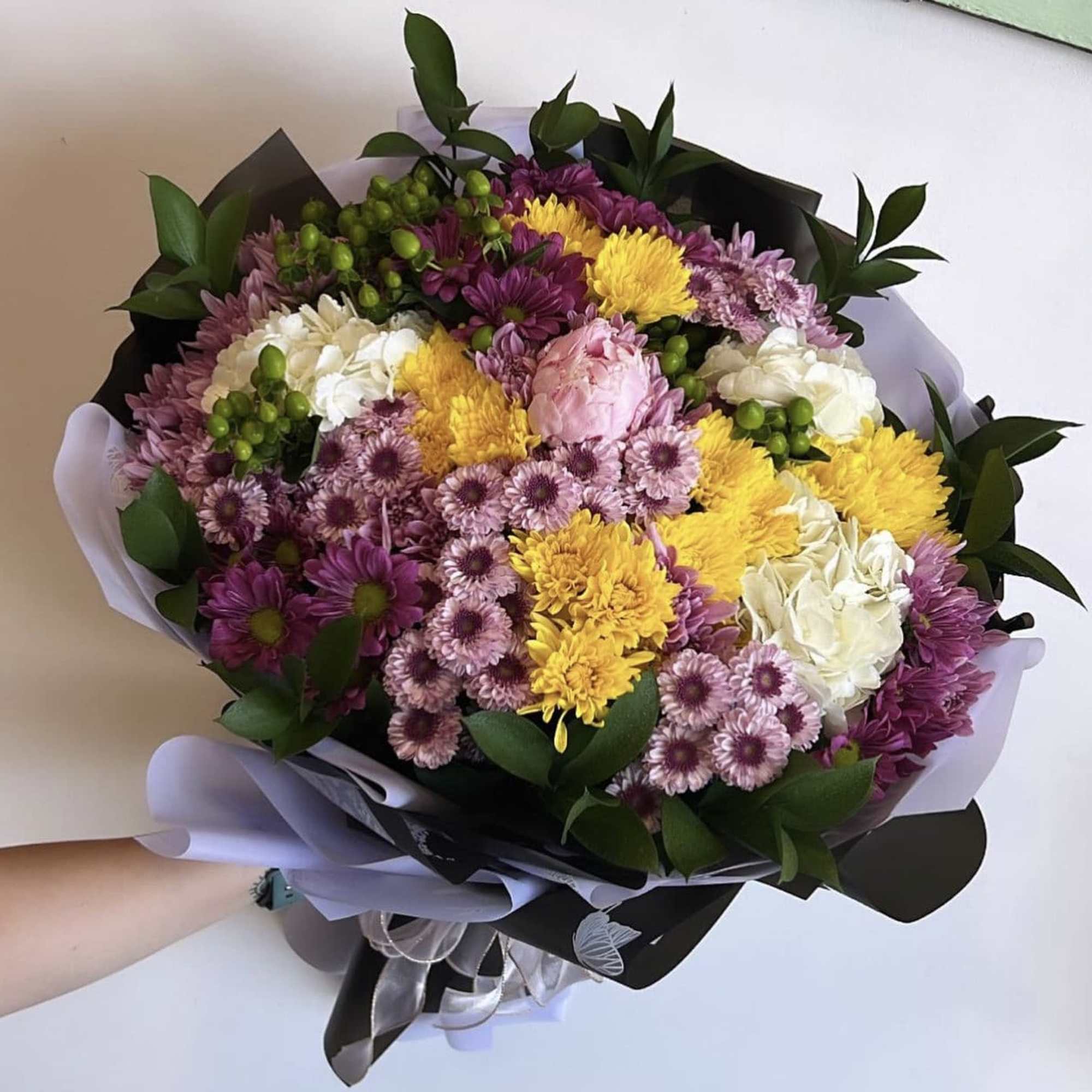 A huge bouquet comprised of buttons, daisies and greenery 