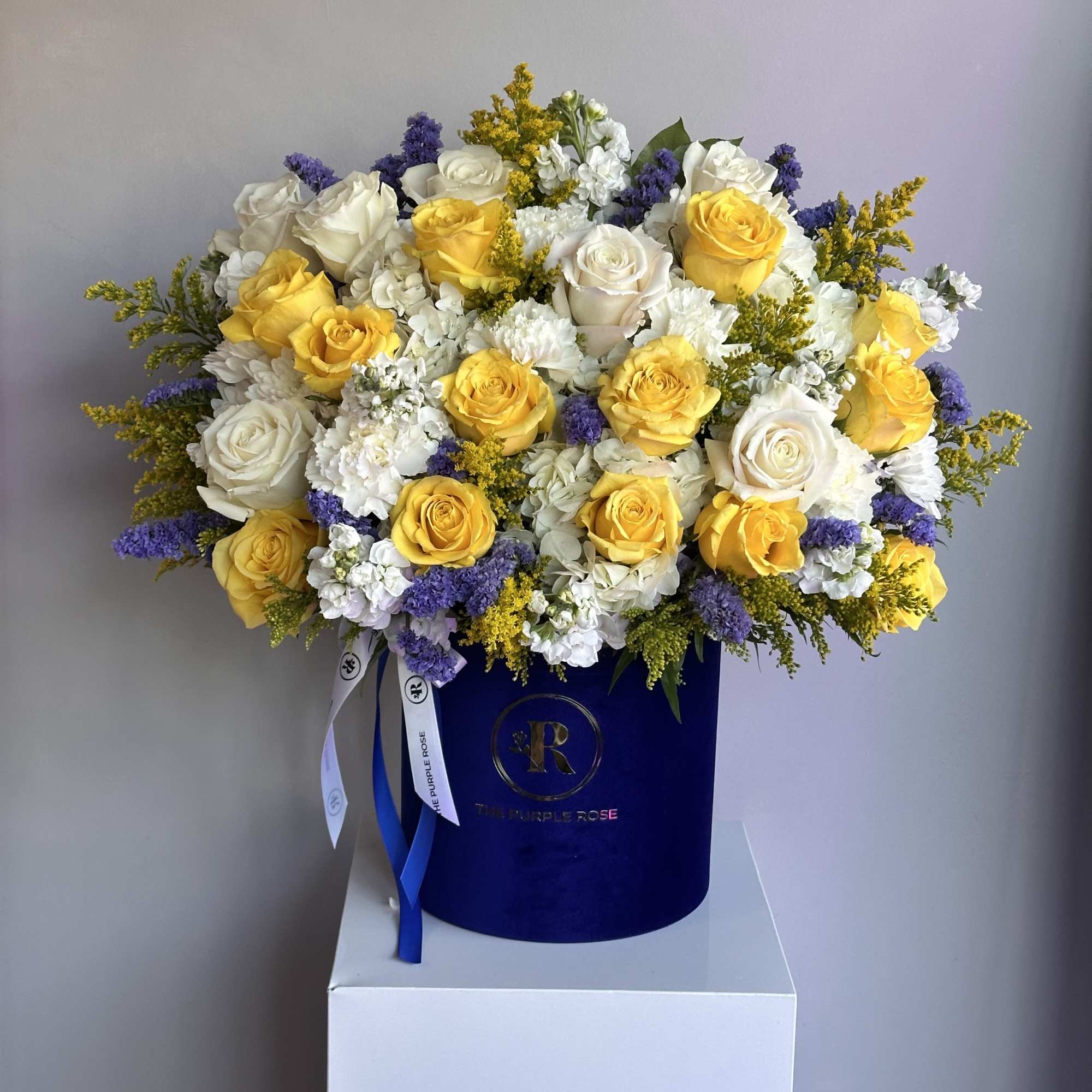 A radiant mix of yellow and white roses with purple accents, elegantly