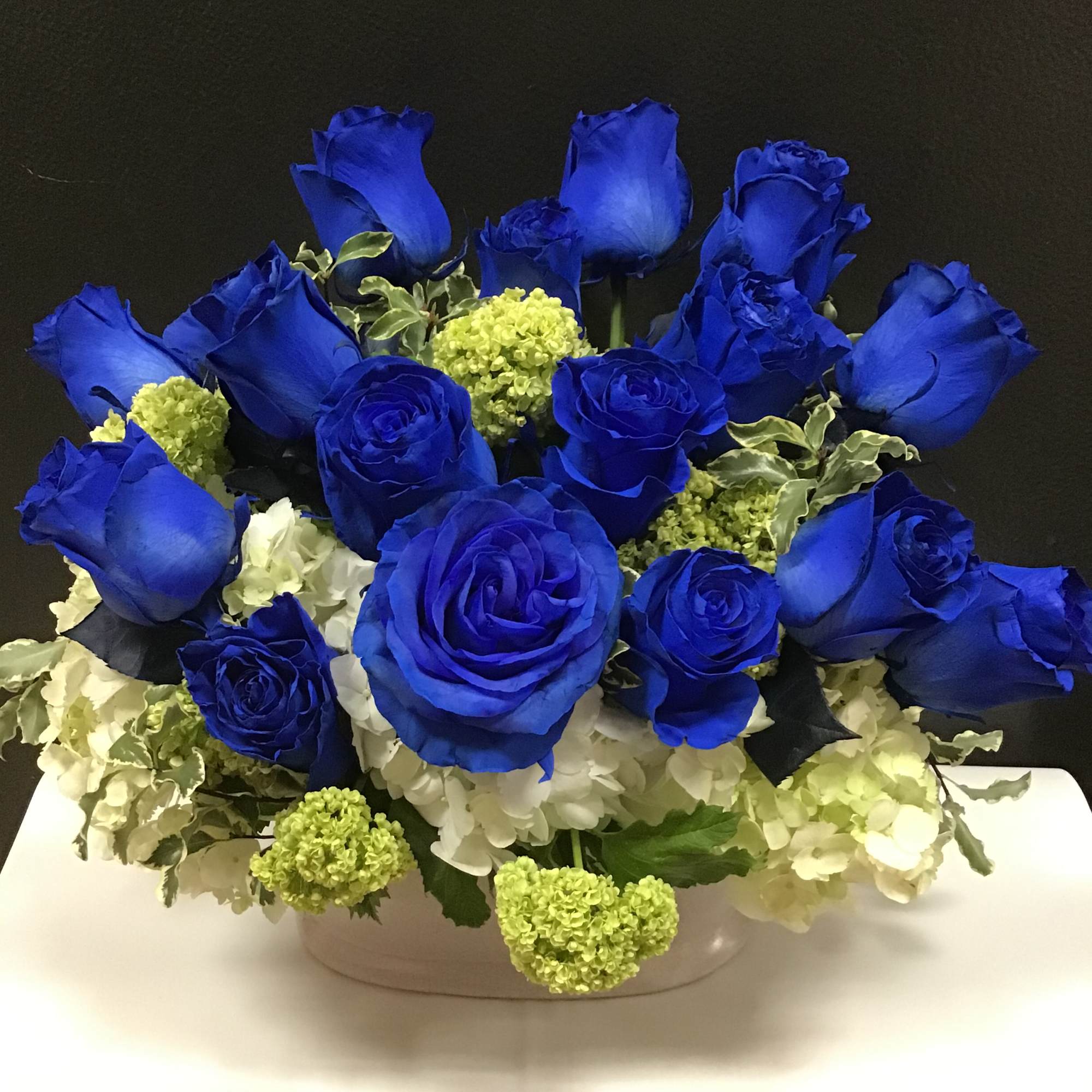 This beautiful arrangement made with blue roses , white and white hydrangea
