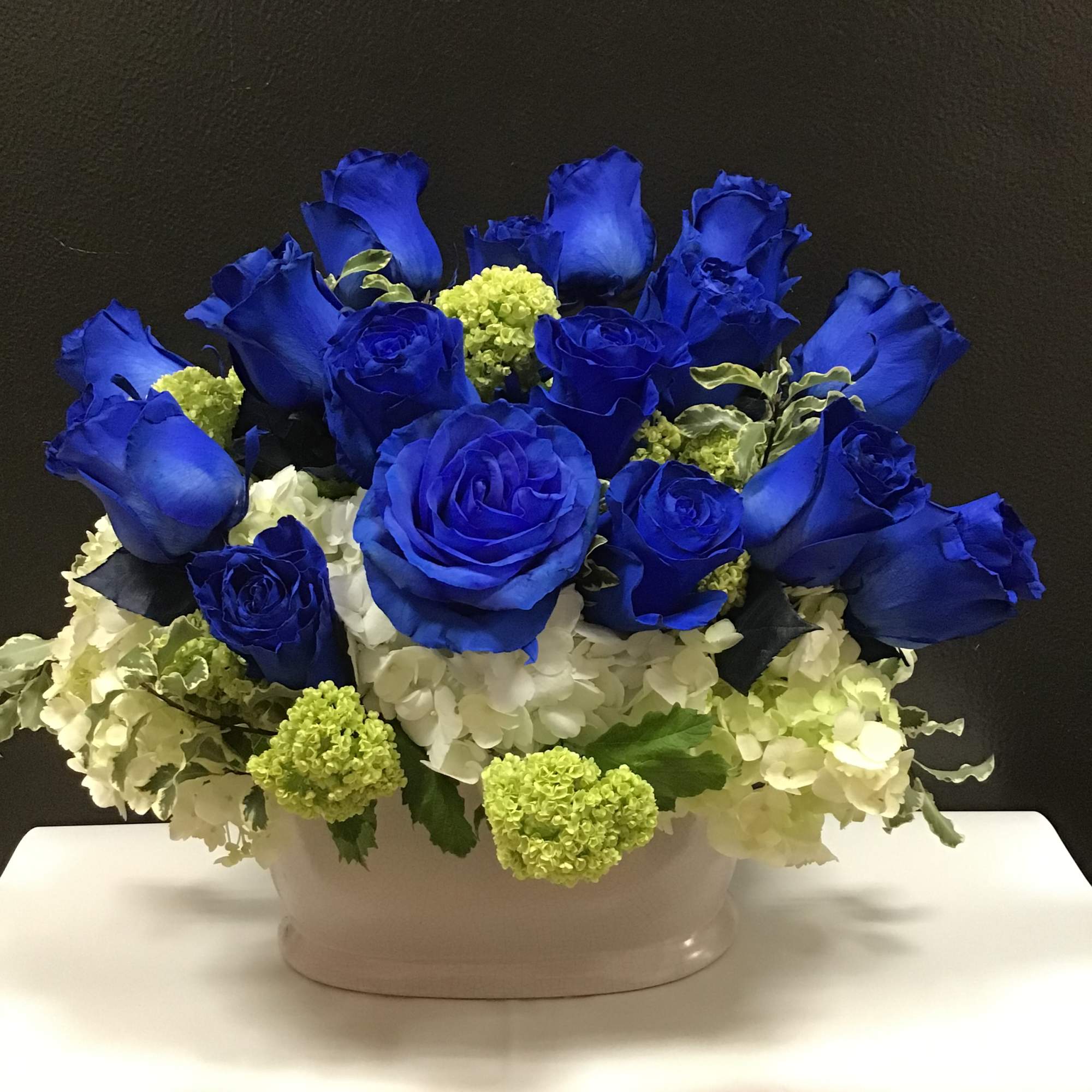 This beautiful arrangement made with blue roses , white and white hydrangea