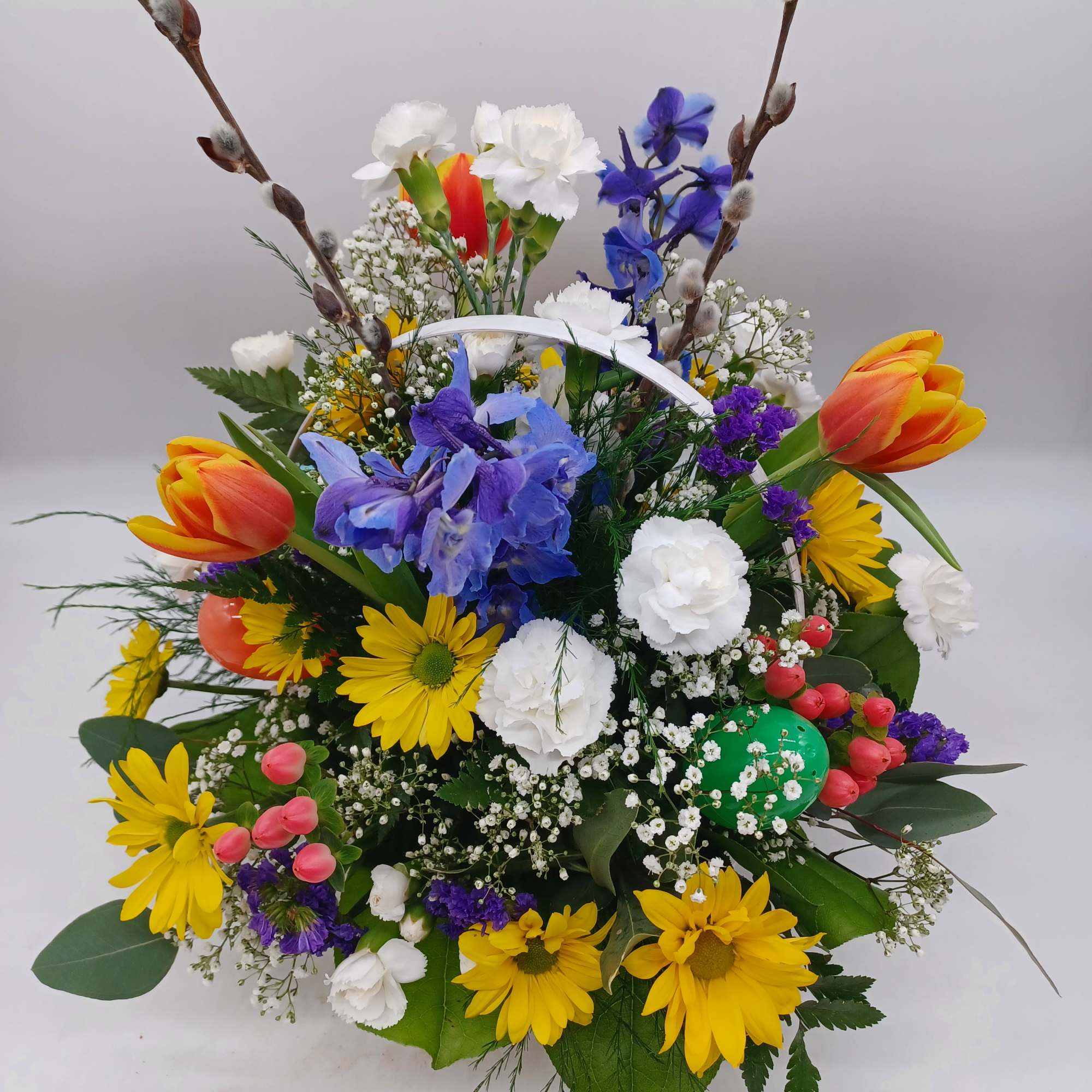 Wicker handled basket filled with Tulips, yellow daisies, delphinium, and other fresh