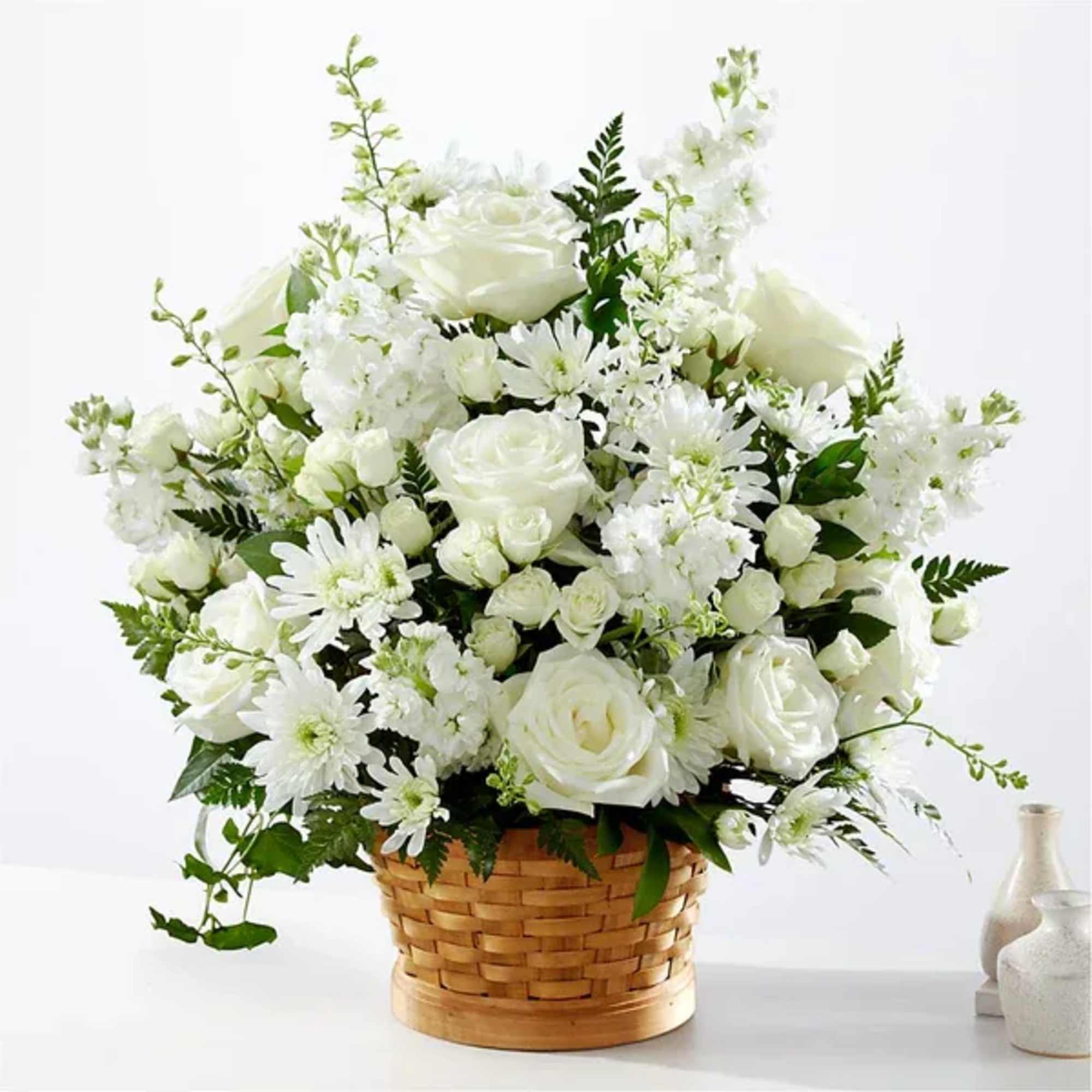 Large white flower arrangement with roses and daisies in a woven basket