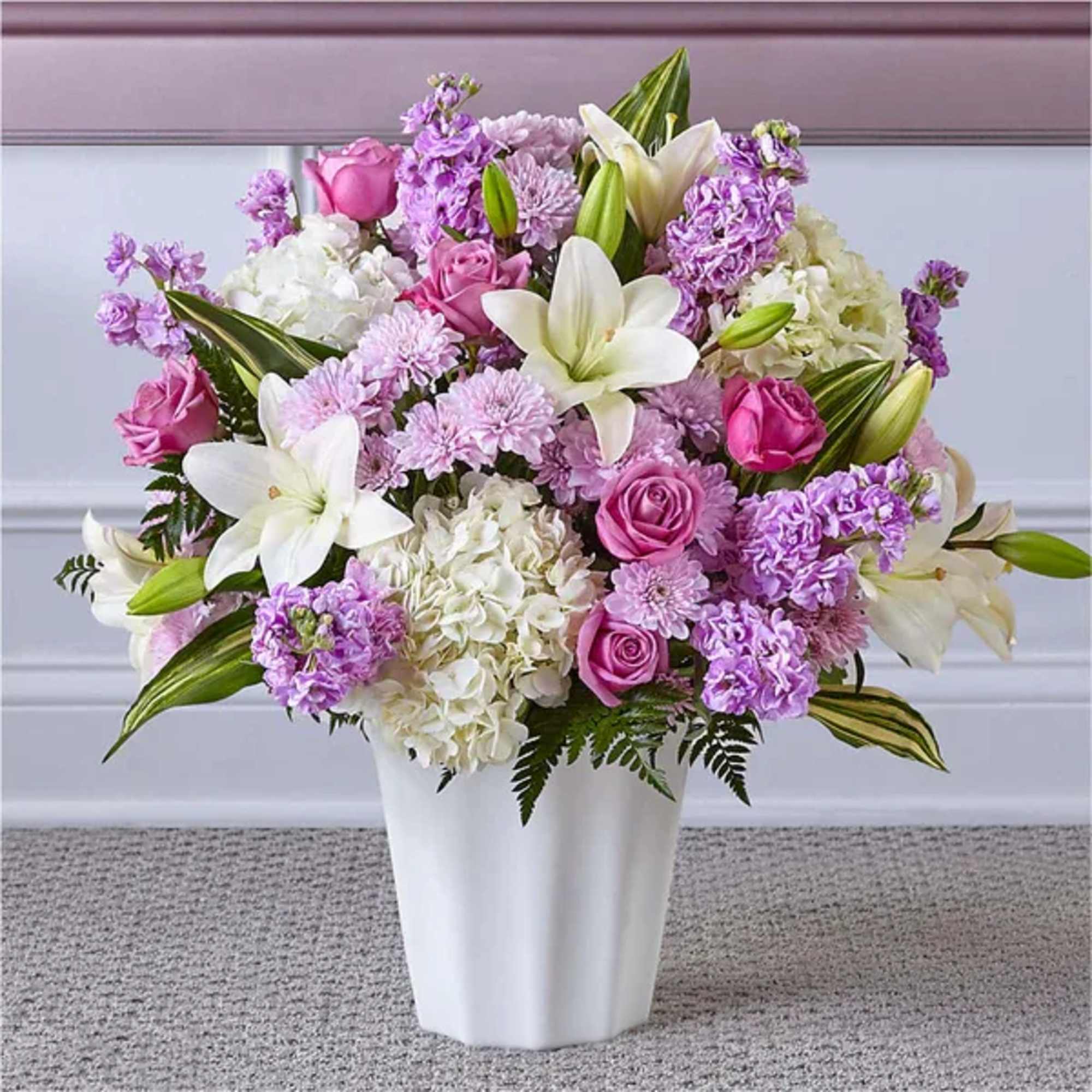 Lavender and white bouquet with lilies, roses, hydrangeas and mums in a white vase
